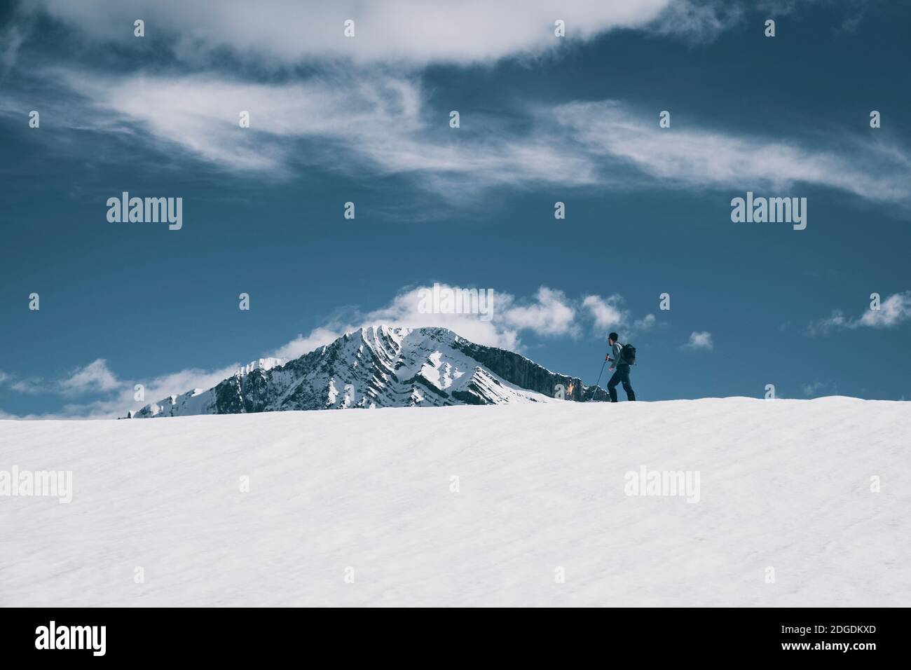 Junger Mann starrt auf schneebedeckten Berg, während er auf einem verschneiten Bergrücken in den Pyrenäen, Huesca, Spanien, spazierengeht Stockfoto