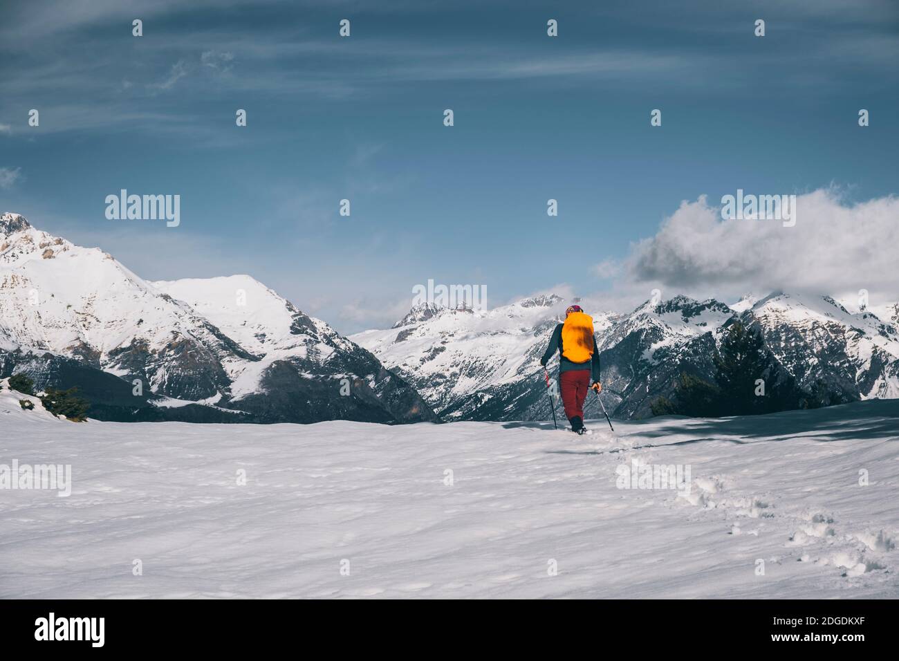 Junger Mann, der im Tiefschnee gegen den schneebedeckten Berg in den Pyrenäen, Huesca, Spanien, läuft Stockfoto