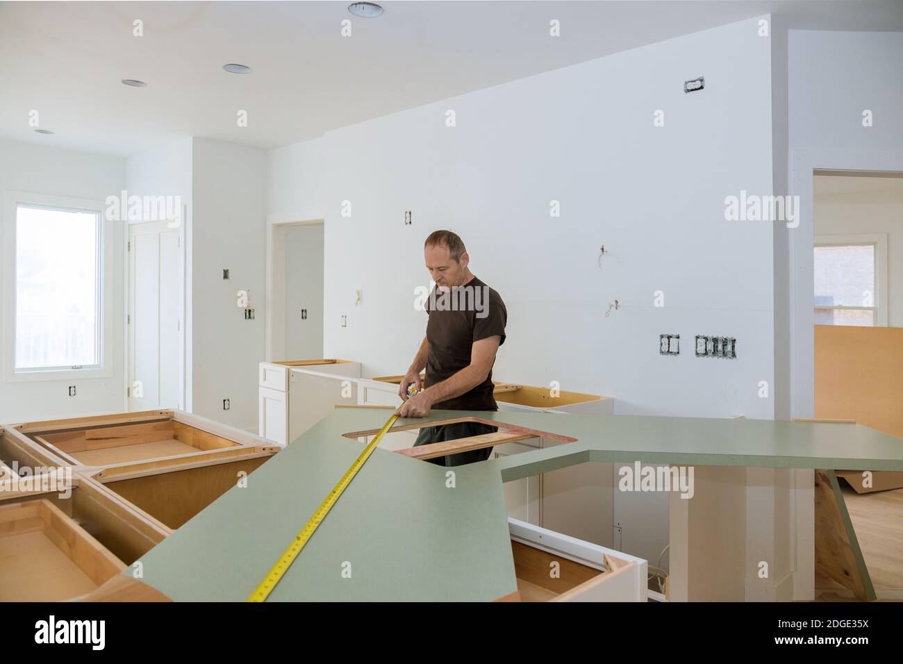 Mann mit Klebeband Maßnahme zur Messung der Größe der hölzernen Arbeitsplatte in der modernen Küche für Home Improvement. Stockfoto