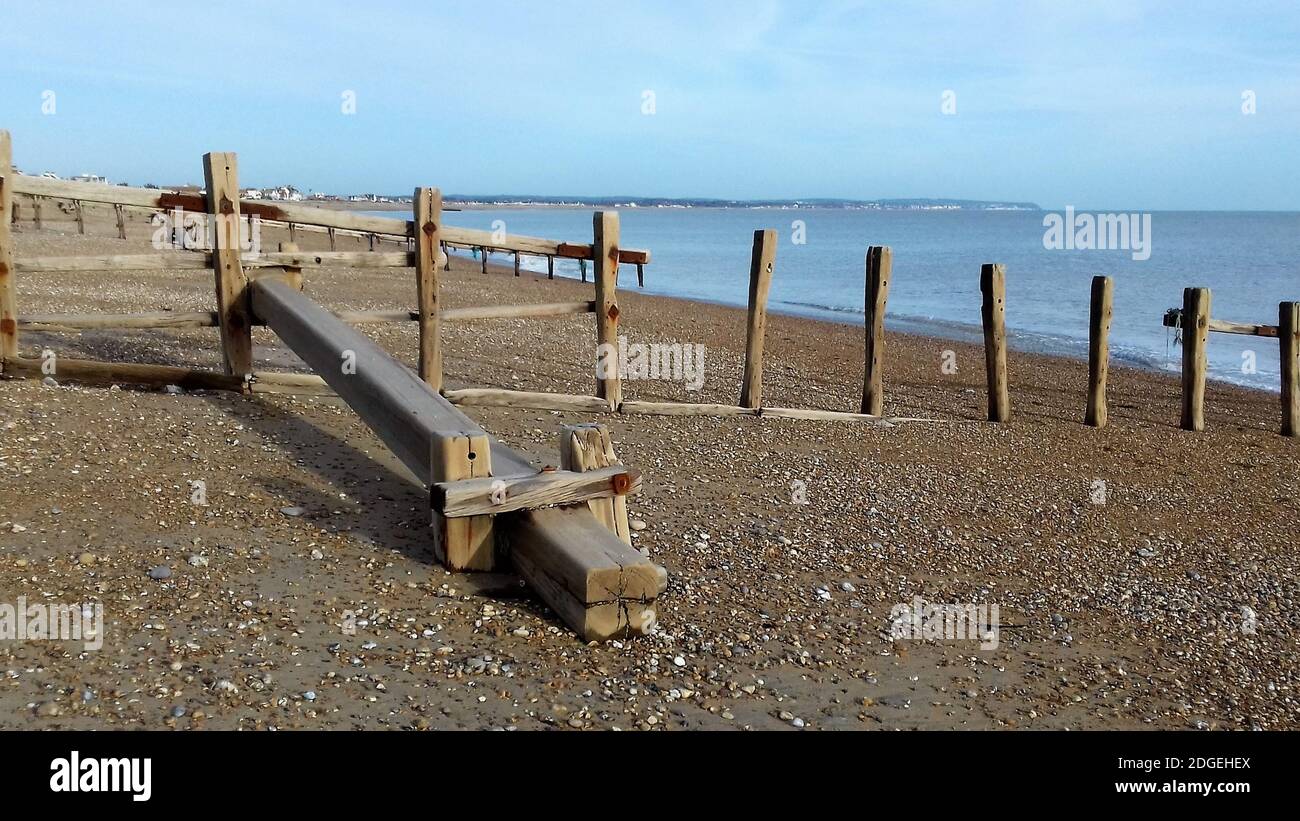 Alte verwitterte Groynes schützen den Strand an der Pevensey Bay an der Südküste Englands. Ohne Groynes würde der Strand an Erosion leiden. Stockfoto