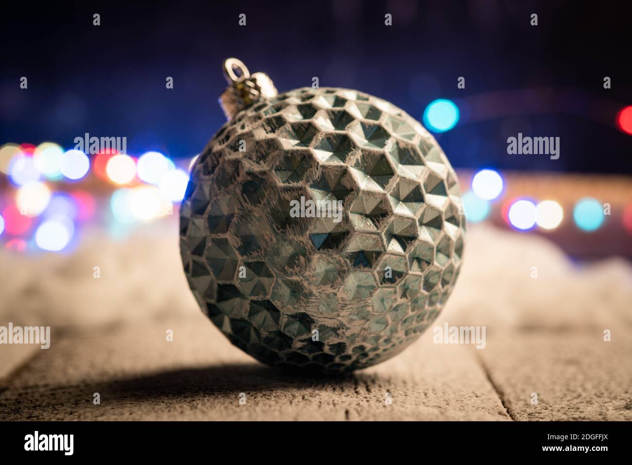 Weihnachtskugeln auf verschneiten Holztisch mit weihnachtsbeleuchtung im Hintergrund. Selektiver Fokus. Geringe Schärfentiefe. Stockfoto