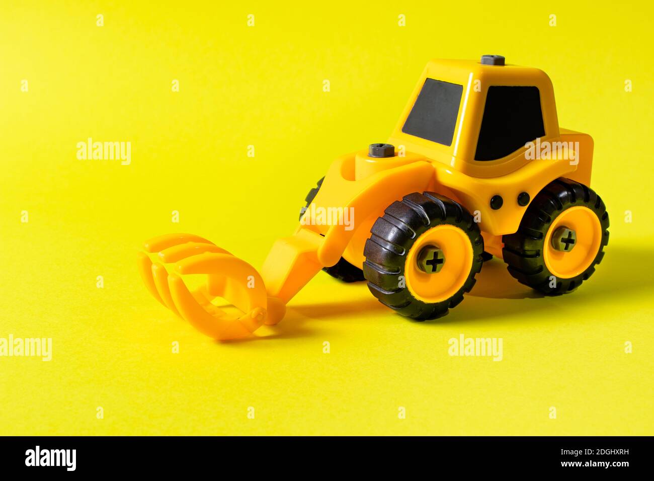 Kinderbaumaschine Holzlader auf gelbem Hintergrund. Traktor für den Jungen und Foto für den Spielwarenladen mit Platz für Textkopie Stockfoto