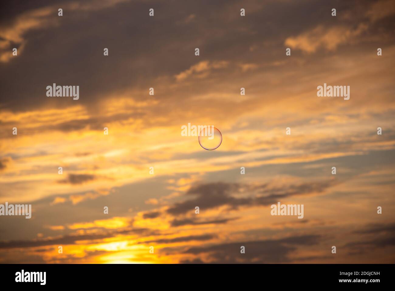 Eine Seifenblase fliegt am dramatisch bewölkten Sonnenuntergang Himmel. Stockfoto