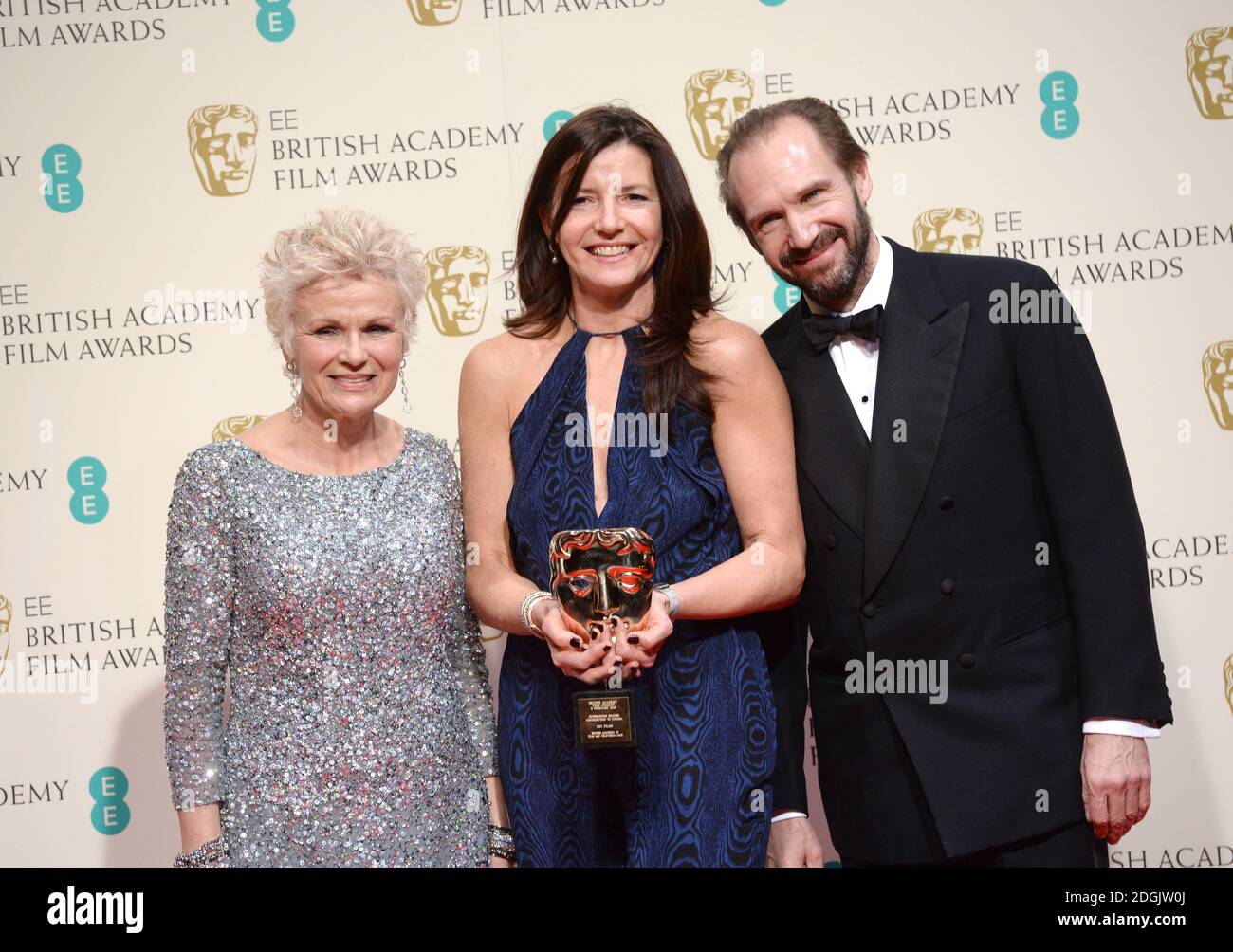 Die britische Produzentin Christine Langan (C) von der BBC posiert mit dem herausragenden britischen Contribution to Cinema Award mit den Moderatoren Ralph Fiennes und Julie Walters im Presseraum der EE British Academy Film Awards 2015 im Royal Opera House in Covent Garden, London. Stockfoto