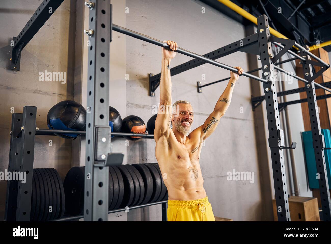 Fröhlicher Sportler lächelt während des Krafttrainings an der Kamera Stockfoto