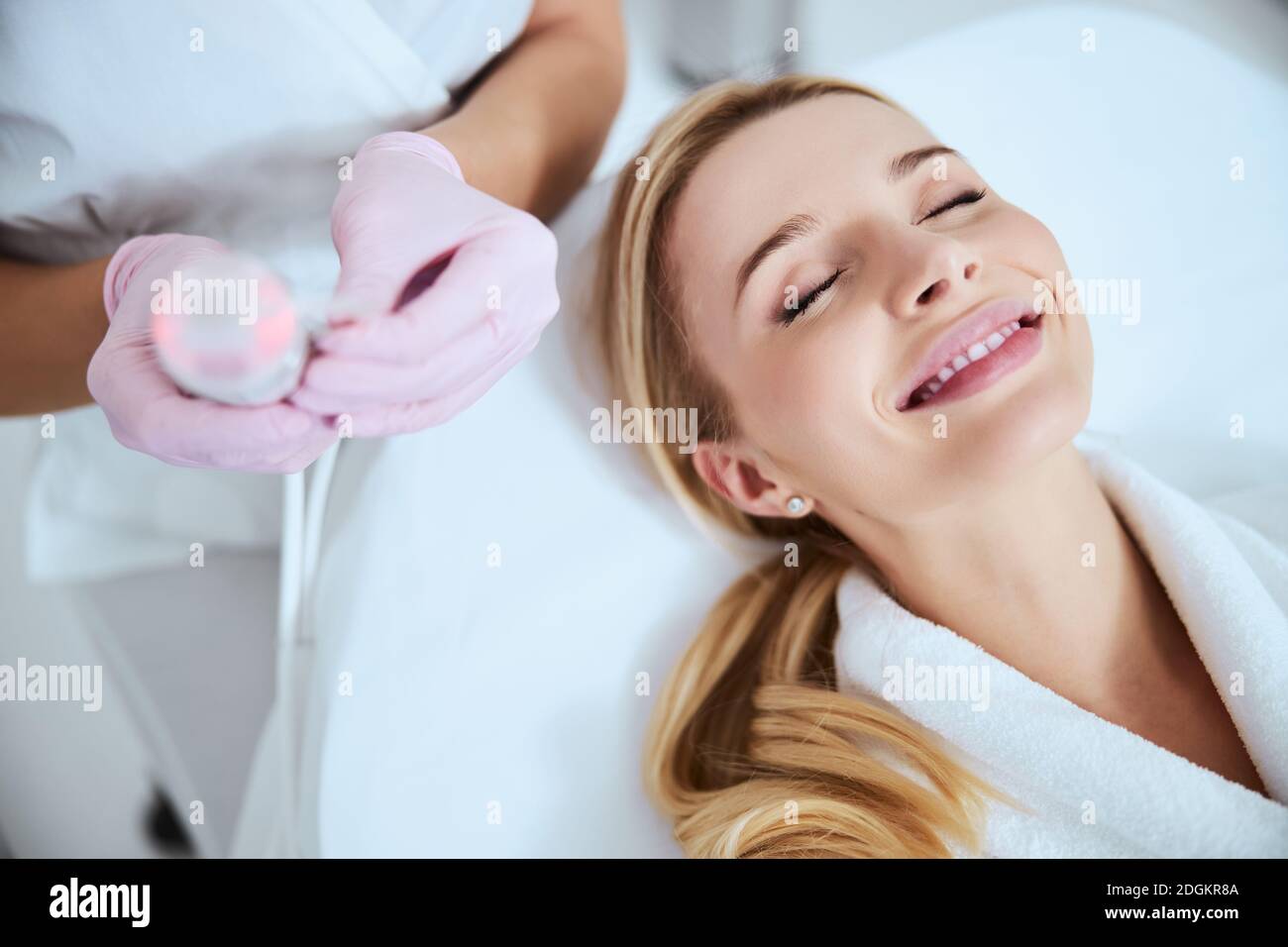 Attraktive blonde Patientin lächelt vor dem kosmetischen Eingriff Stockfoto