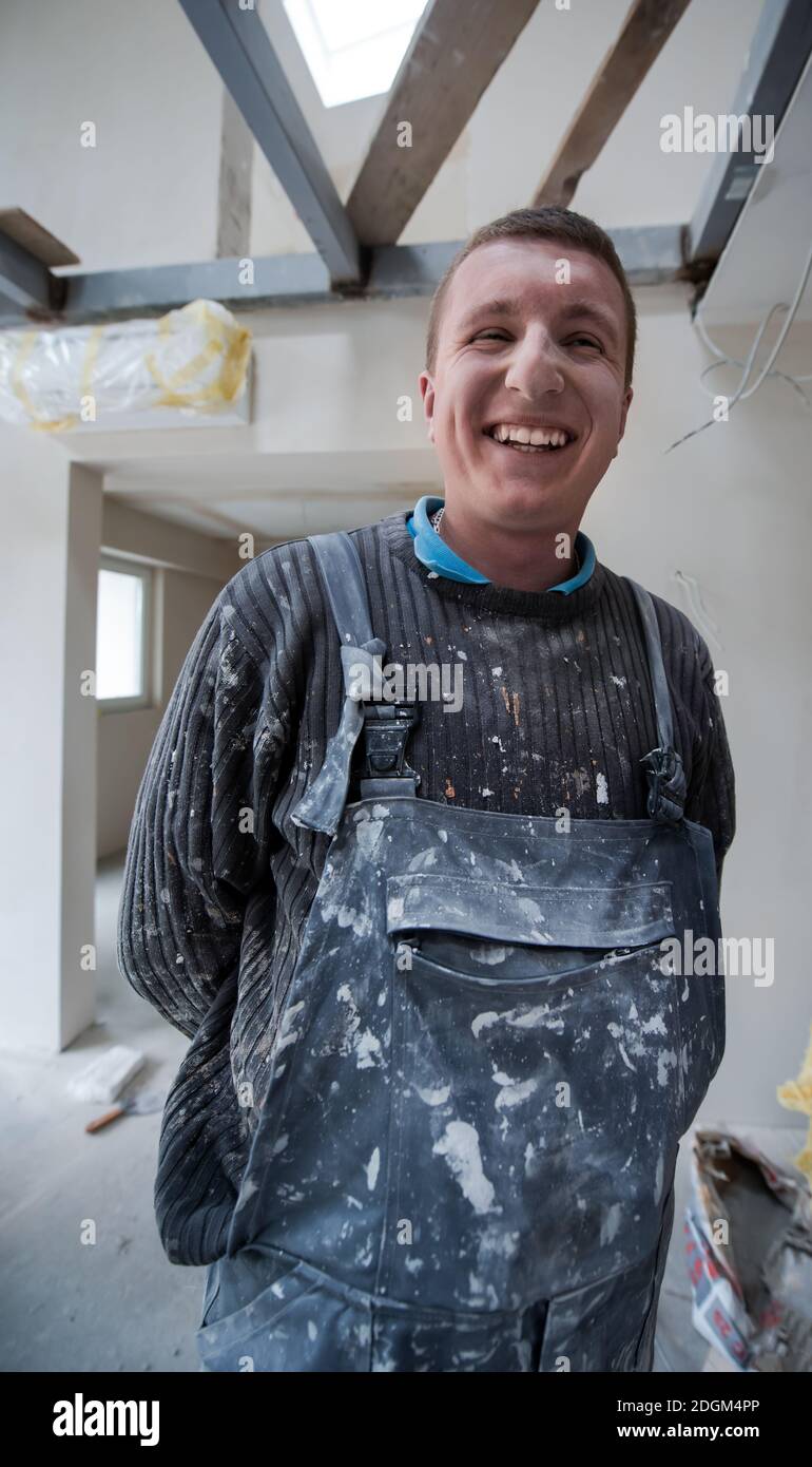 Portrait des Bauarbeiters mit schmutziger Uniform in der Wohnung Stockfoto