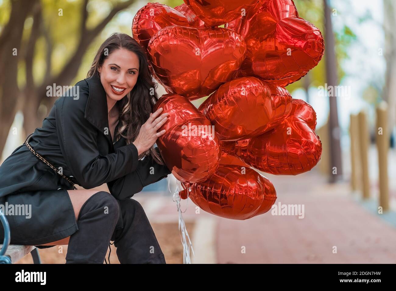 Schöne hispanische Brünette Modell feiert Valentinstag mit EINEM Dutzend Rote Herzballons Stockfoto
