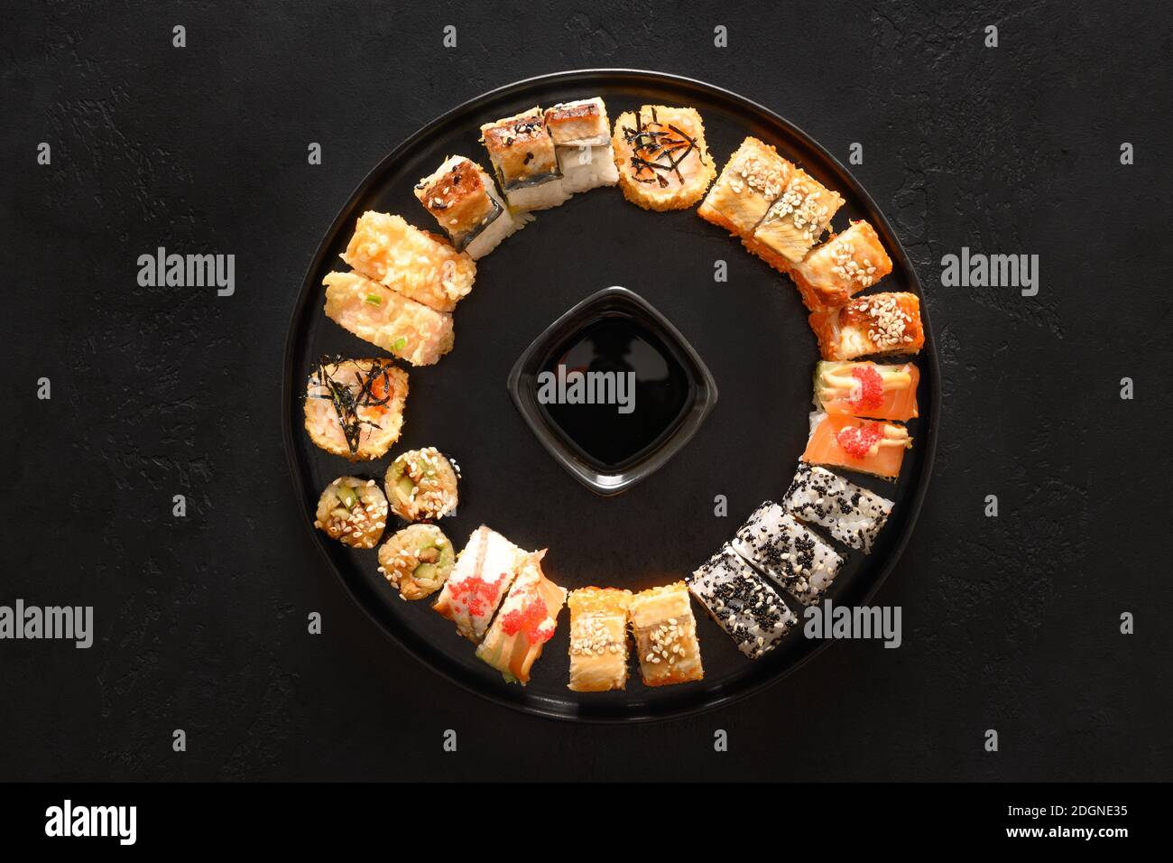 Sushi-Set als Weihnachtskranz serviert mit Sojasauce auf schwarzem Hintergrund. Blick von oben. Stockfoto