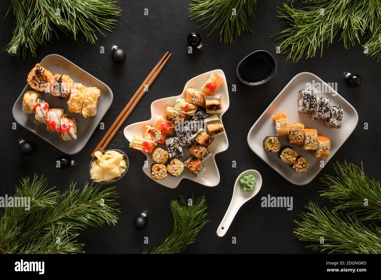 Festliches Weihnachtsessen mit Sushi-Set mit Weihnachtsdekoration auf schwarzem Hintergrund. Blick von oben. Flache Lay-Optik. Silvesterparty. Stockfoto