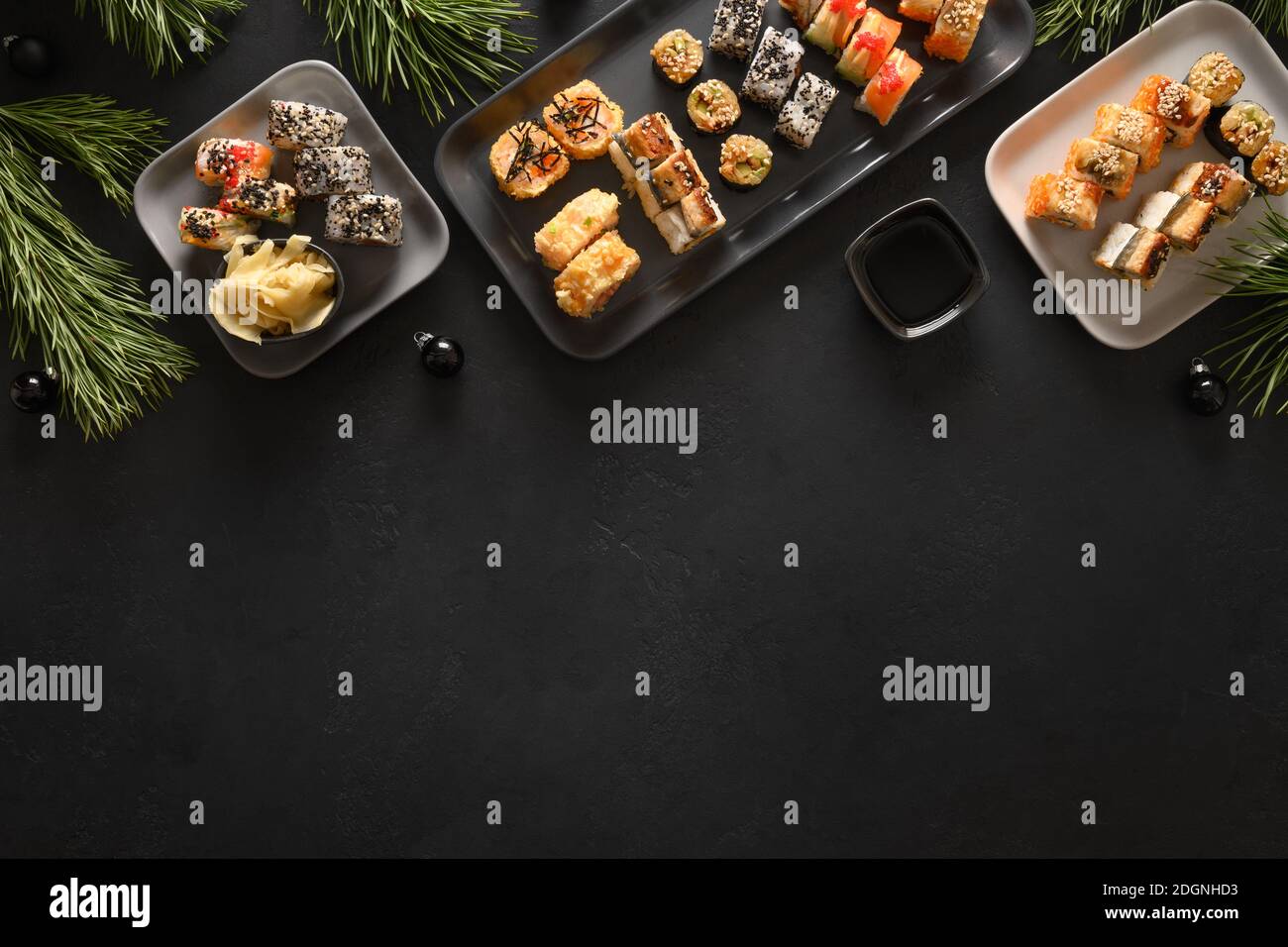 Festliche Weihnachten asiatische Lebensmittel mit Sushi-Set, Weihnachtsdekoration auf schwarzem Hintergrund. Blick von oben. Flache Lay-Optik. Silvesterparty. Stockfoto