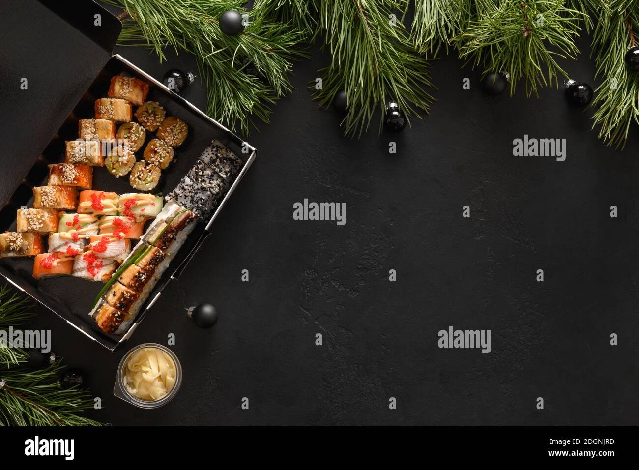 Food Delivery für asiatische Sushi-Set für Weihnachtsessen oder Silvester-Party auf schwarzem Hintergrund. Blick von oben. Flache Lay-Optik. Speicherplatz kopieren. Stockfoto