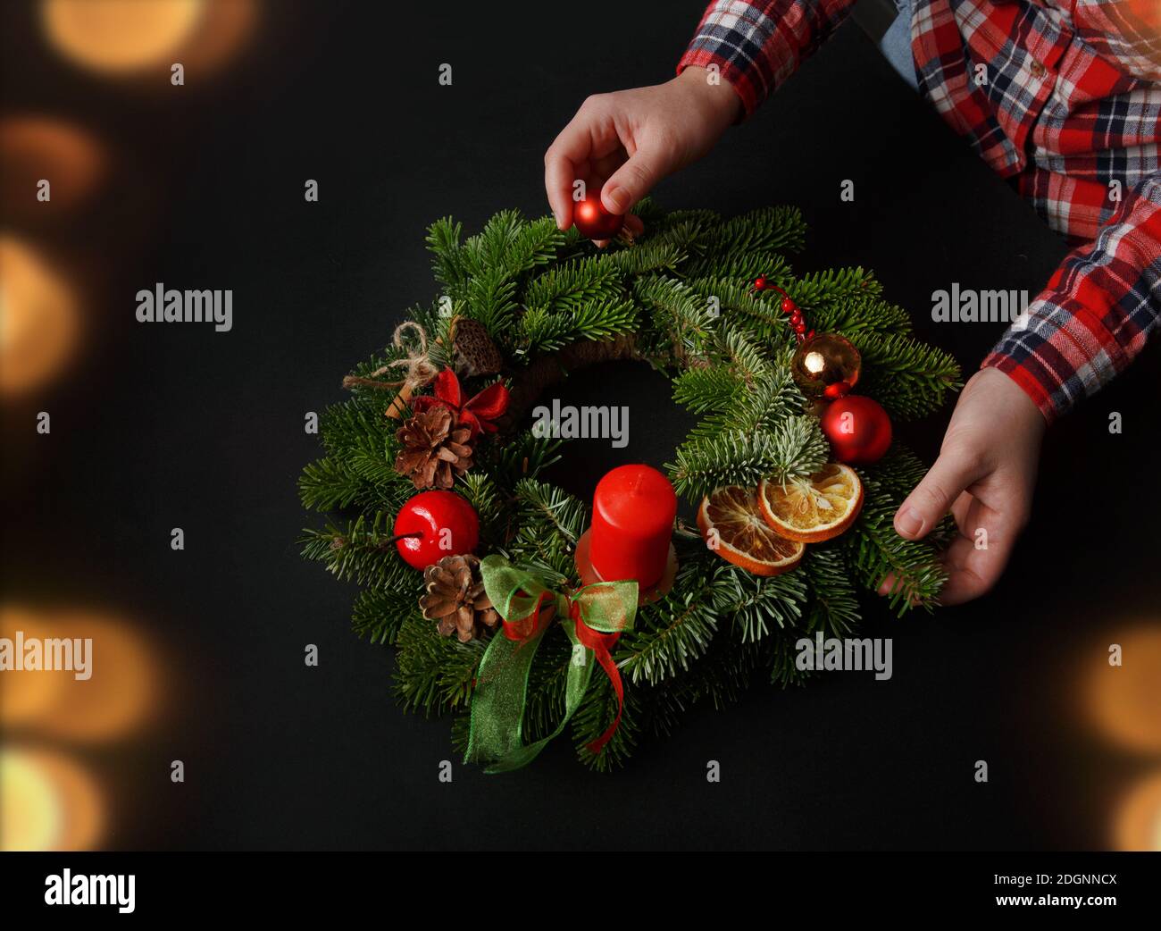 Schöner Weihnachtskranz in Frauenhänden. Festliche Inneneinrichtung. Stockfoto
