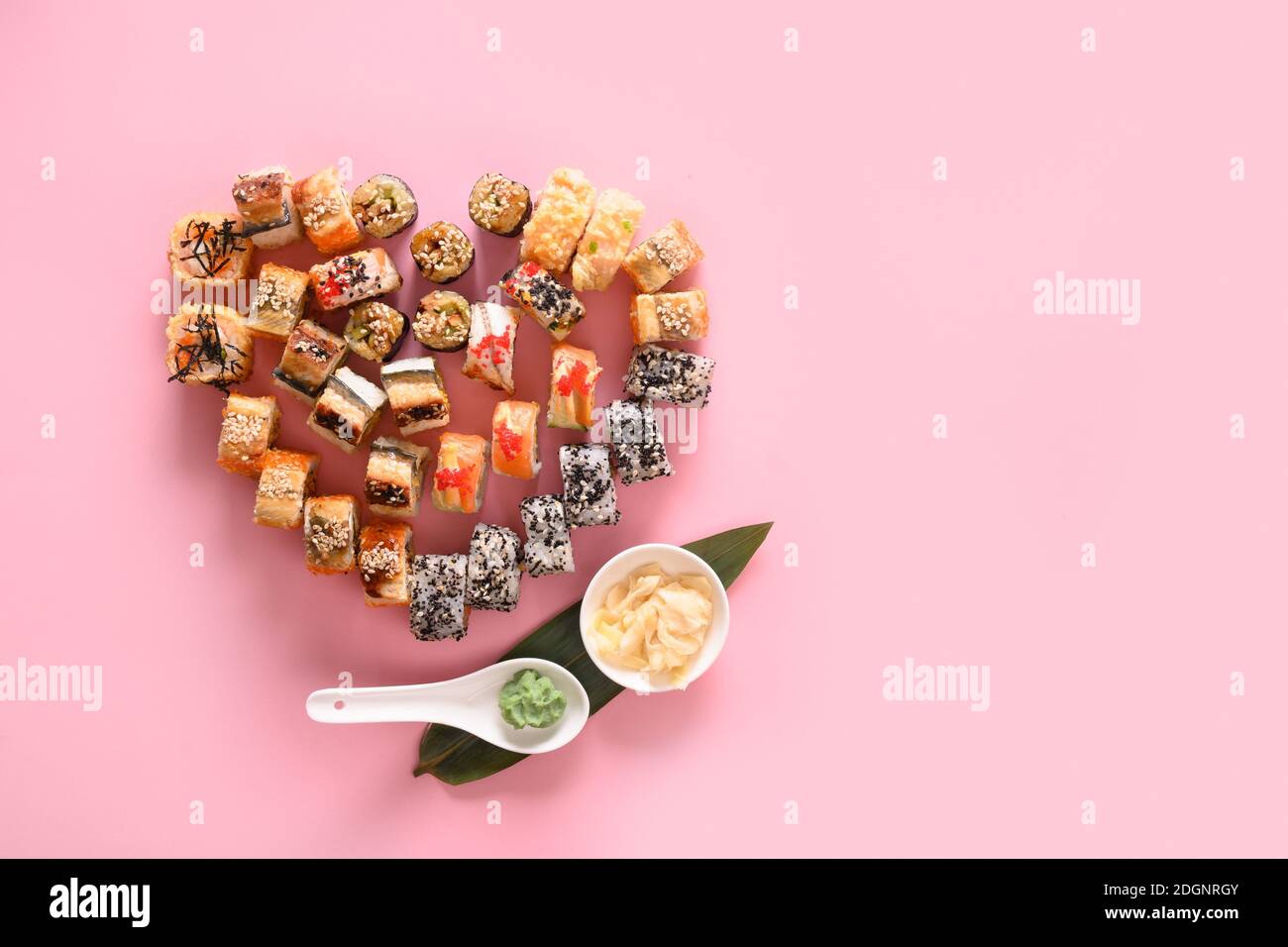 Sushi auf dem Teller als Herz serviert Ingwer, Wasabi auf rosa Hintergrund. Valentine Day Food Konzept. Blick von oben. Leerzeichen für Text. Flatlay-Style. Stockfoto