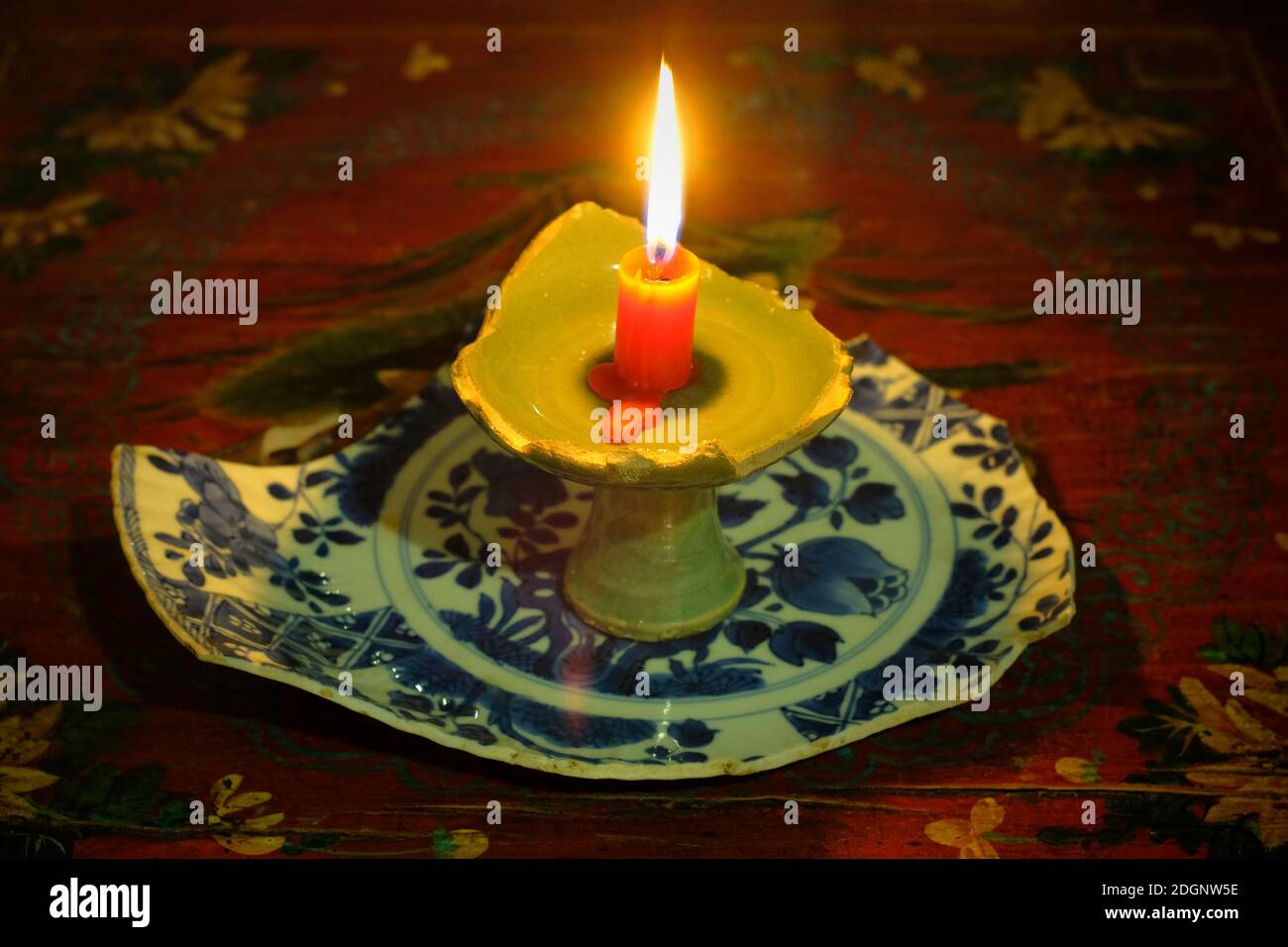 Ein Kerzenständer aus einem gebrochenen Yuan-Dynastie Longquan Brennofen Kelch über einem Stück blauen und weißen Teller der Ming-Dynastie. Stockfoto