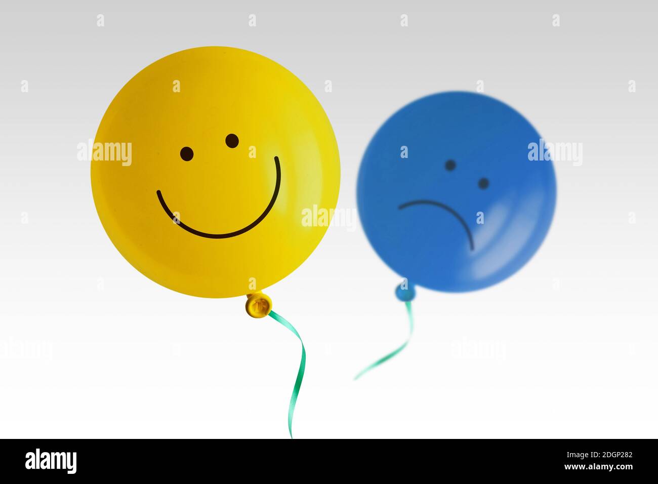 Gelber glücklicher Ballon und blauer trauriger Ballon fliegen fort Weißer Hintergrund - Prävalenz der positiven über negativen Stimmung conept Stockfoto