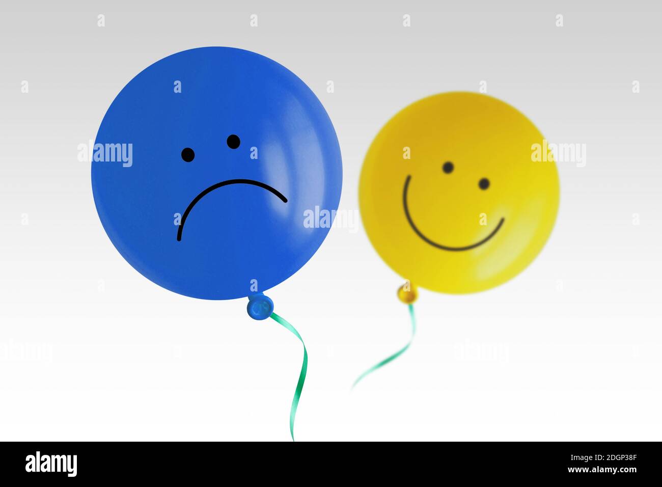 Blauer trauriger Ballon und gelber glücklicher Ballon fliegen fort Weißer Hintergrund - Prävalenz der negativen über positive Stimmung Konzept Stockfoto