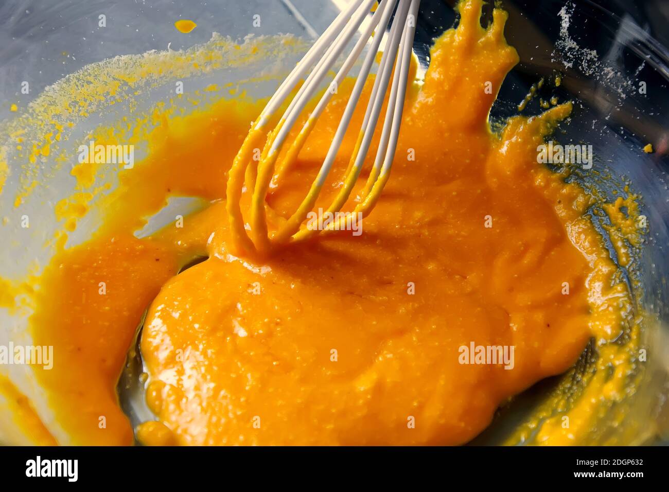 Eigelb mit einem Silikon-Schneebesen in einer transparenten Schüssel Stockfoto
