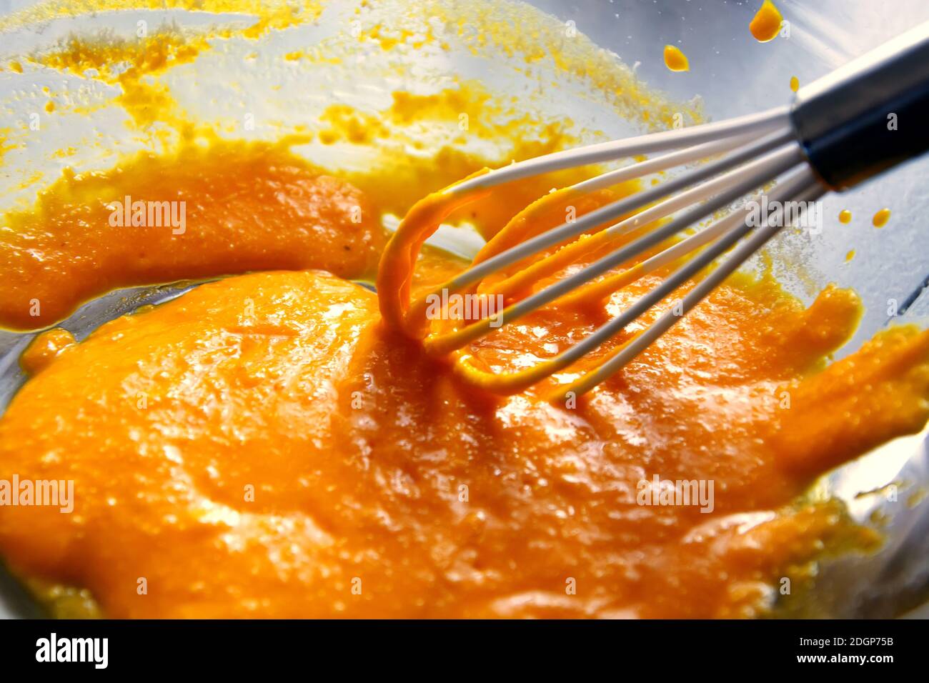Eigelb mit einem Silikon-Schneebesen in einer transparenten Schüssel Stockfoto