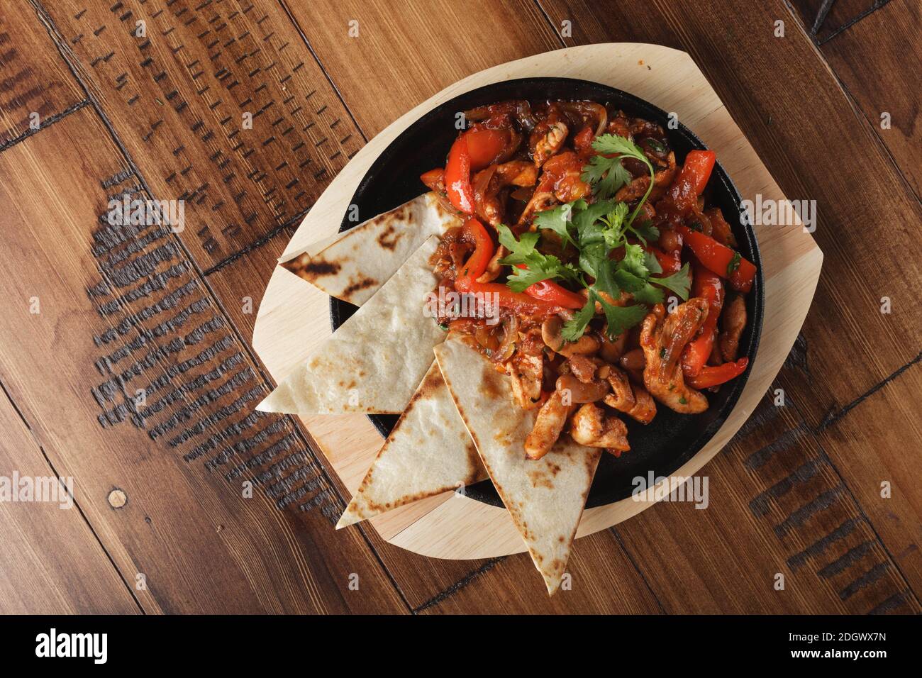 Fajitas mit Huhn und Paprika in einer Pfanne. Holzhintergrund. Stockfoto