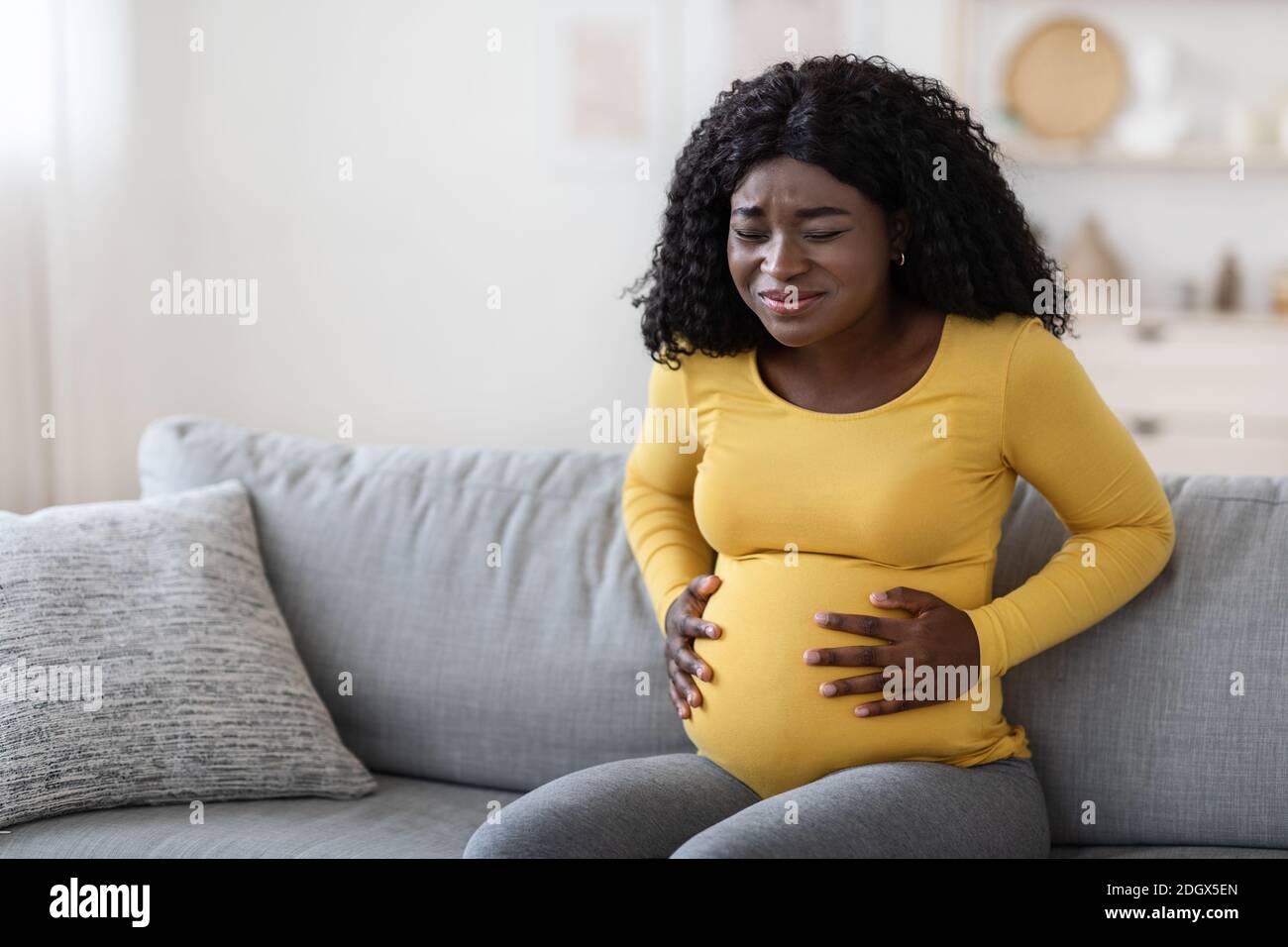 Schwarze schwangere Frau, die an Wehen zu Hause leidet Stockfoto