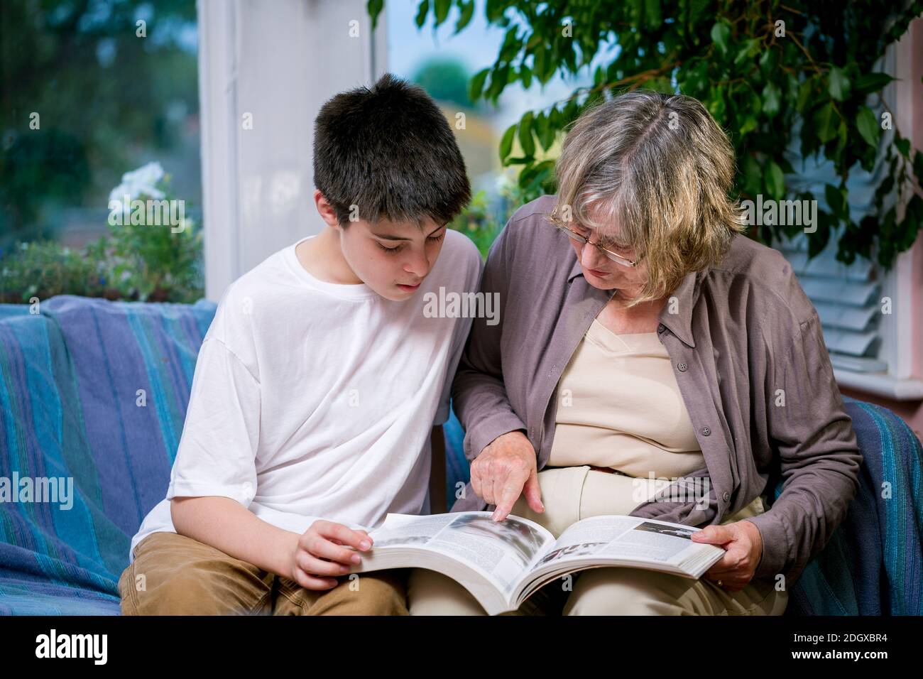 Eine Gro mutter und ein Enkel  lesen zusammen auf einem 