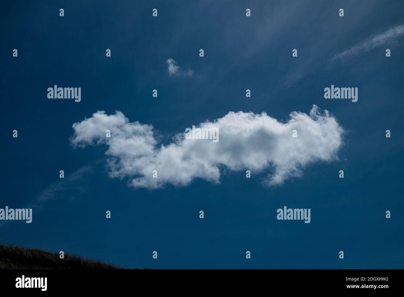 Definierte einzelne weiße Wolke auf einem tiefblauen Himmel Stockfoto