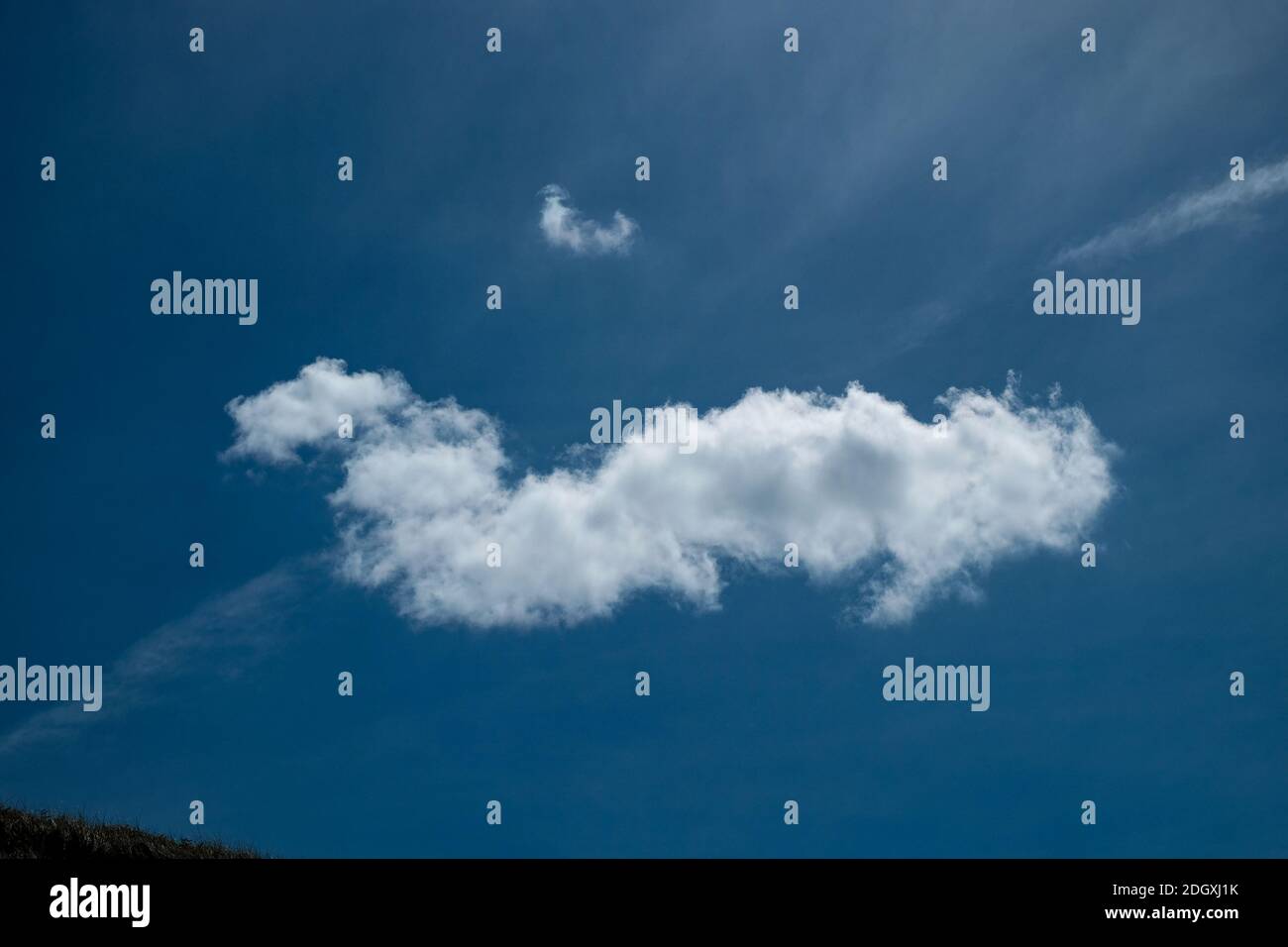 Definierte einzelne weiße Wolke auf einem tiefblauen Himmel Stockfoto