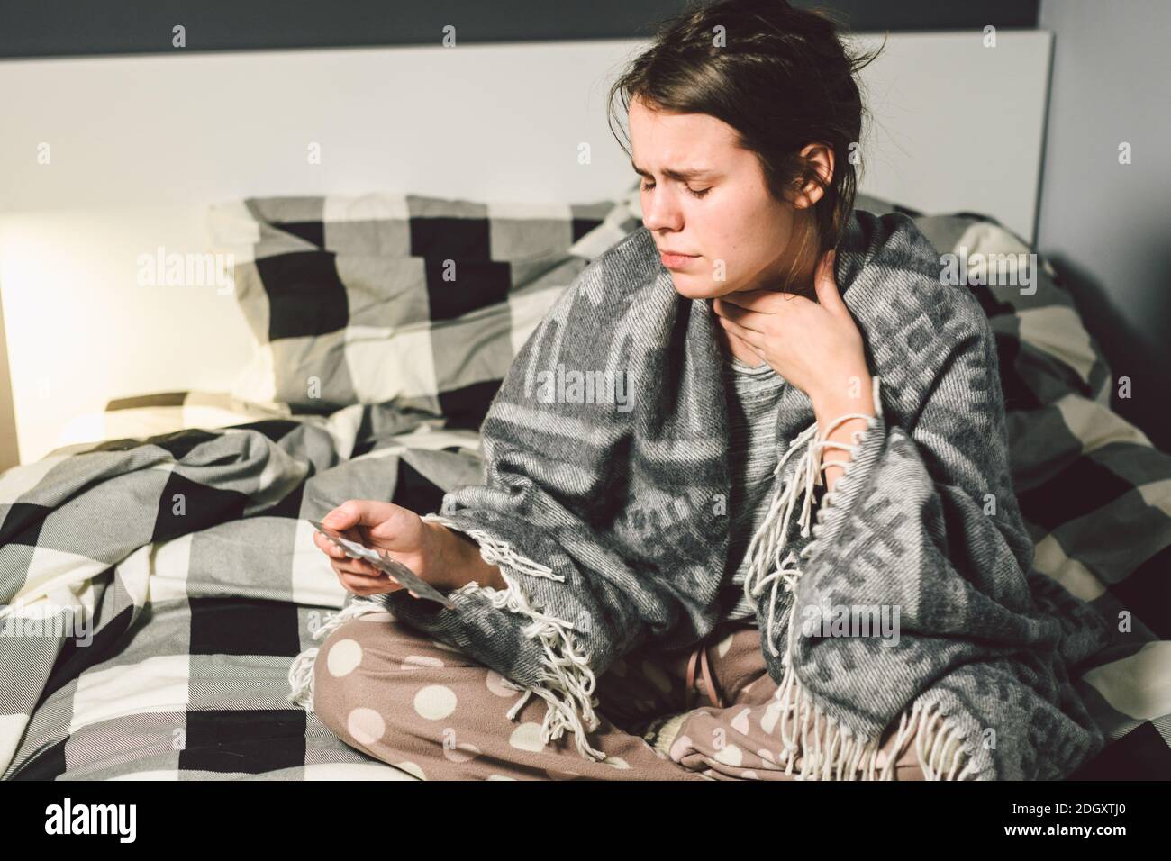 Das Thema ist Atemwegserkrankungen und Hausmittel. Schöne junge Frau ist krank mit einer Erkältung sitzen im Schlafzimmer auf dem Bett Stockfoto