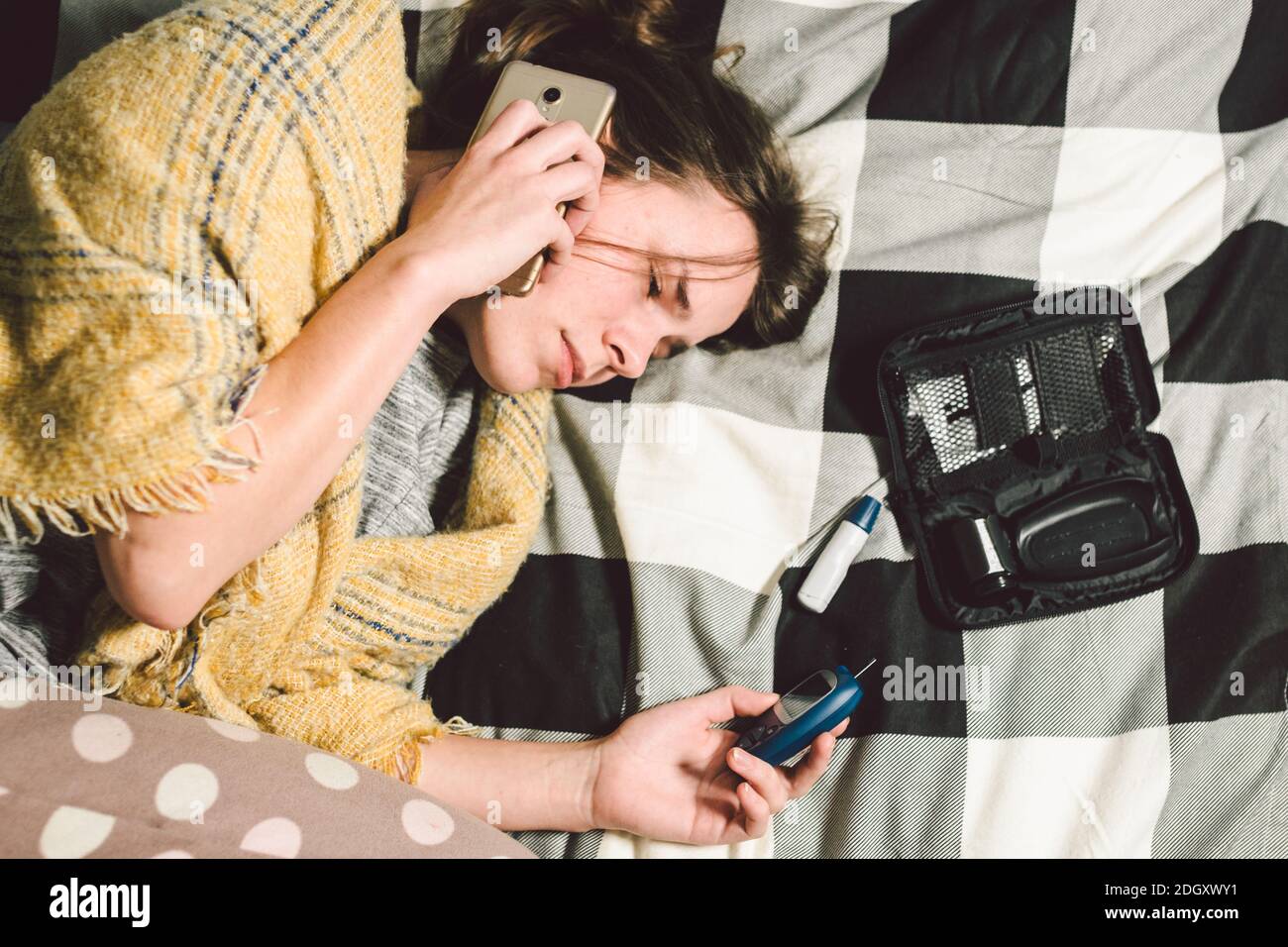 Thema Diabetes. Junge Frau zu Hause Schlafzimmer Bett nutzt Technologie Gerät Messung Blutzuckerspiegel, Glucometer Teststreifen hoch Stockfoto