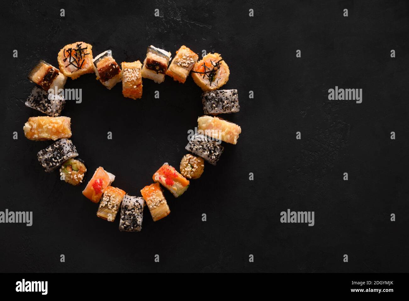 Sushi Set als Herz auf schwarzem Hintergrund. Valentine Day Food Konzept. Blick von oben. Leerzeichen für Text. Flache Lay-Optik. Stockfoto