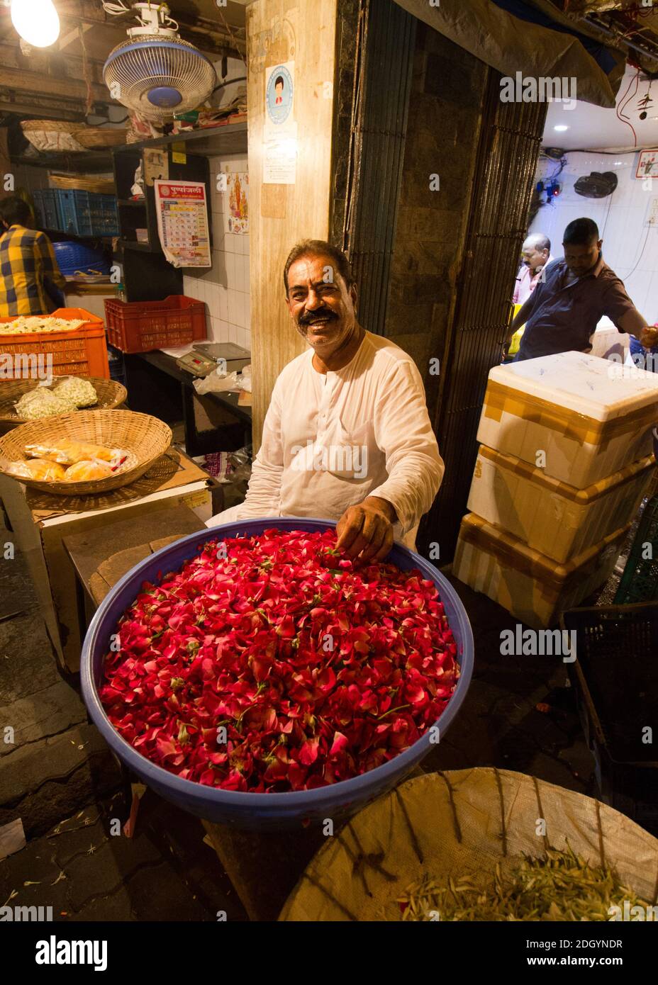 Ein strahlender Blumenhändler sitzt an seinem Stand auf dem Dadar Flower Market in Mumbai Stockfoto