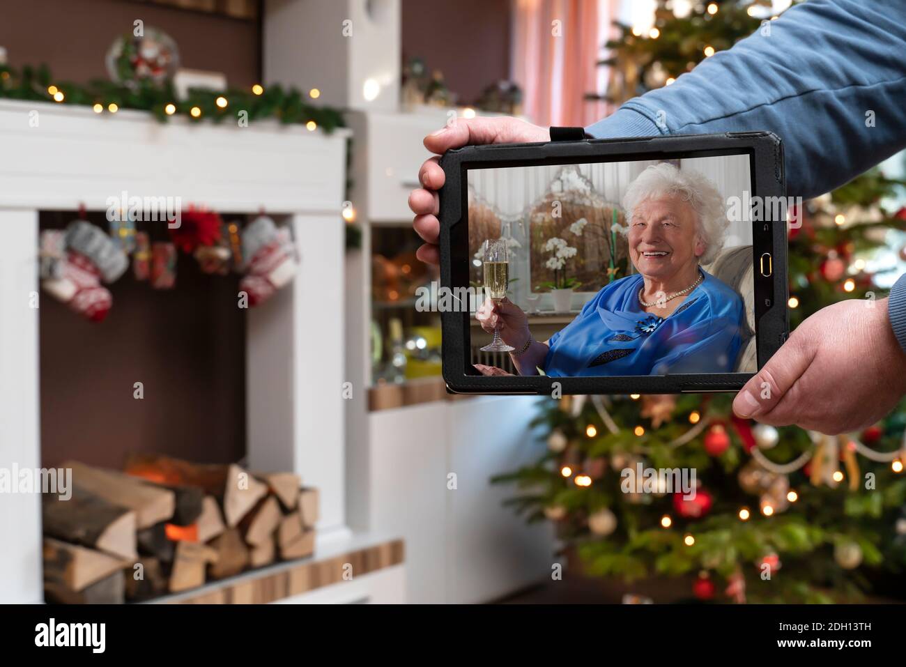 Weihnachtszeit, ein Mann hält eine Tablette. Während der Corona-Pandemie kommt die Familie zu Weihnachten nicht zusammen. Die Großmutter ist online durch das fa Stockfoto