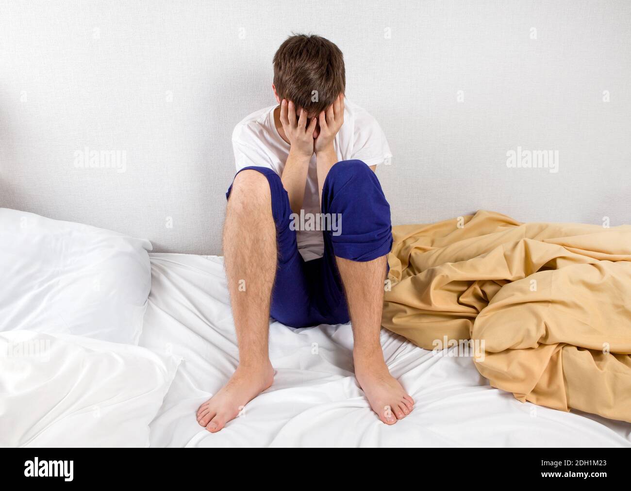 Trauriger junger Mann Sit on the Bed at the Home Stockfoto