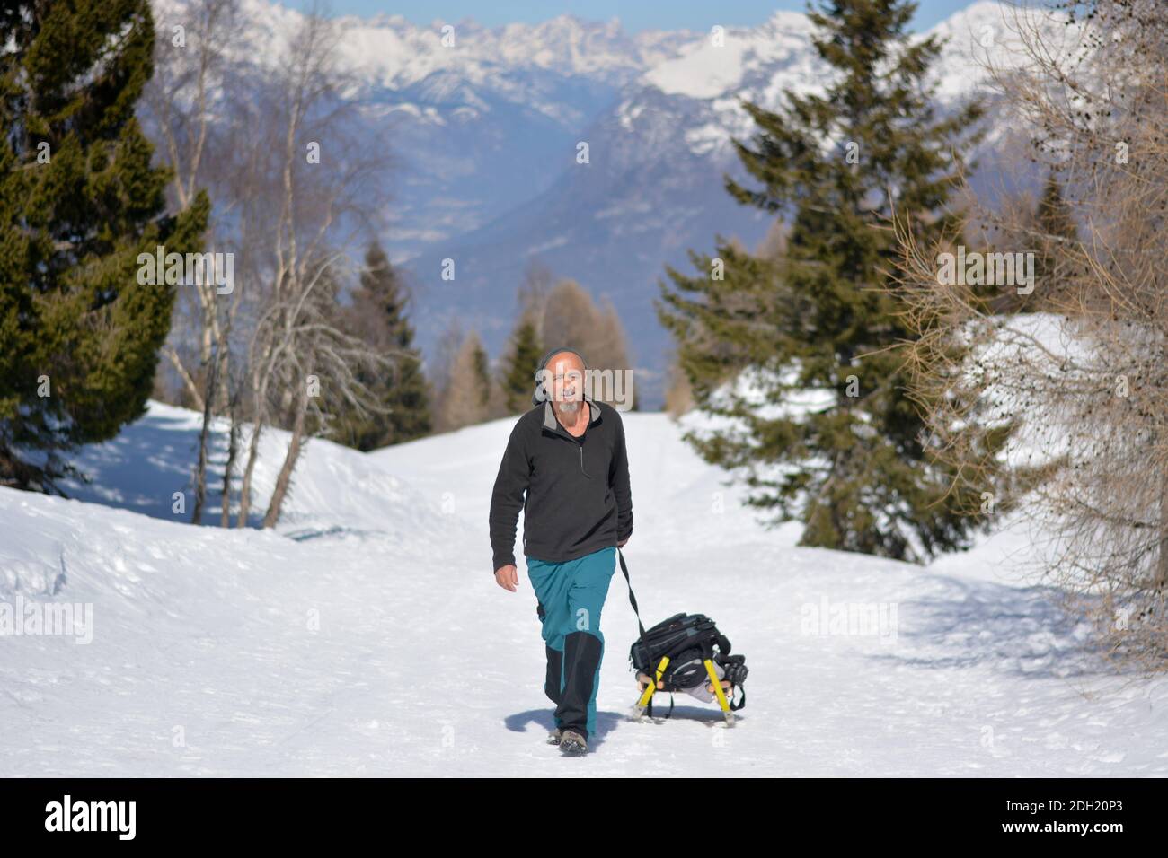 Der Mensch geht mit dem Schlitten auf den Berg Stockfoto