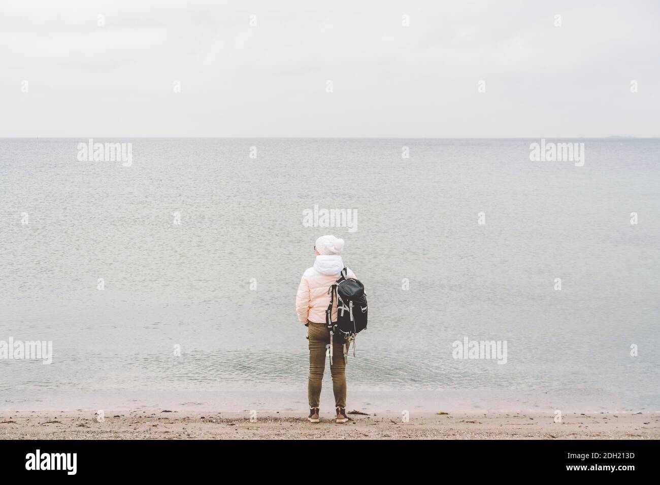 Ein kaukasischer Mann, eine junge kaukasische Frau, die im Winter mit einem  schwarzen Rucksack an einem sandigen Strand in der Nähe der Ostsee  unterwegs ist. Themenreise Stockfotografie - Alamy