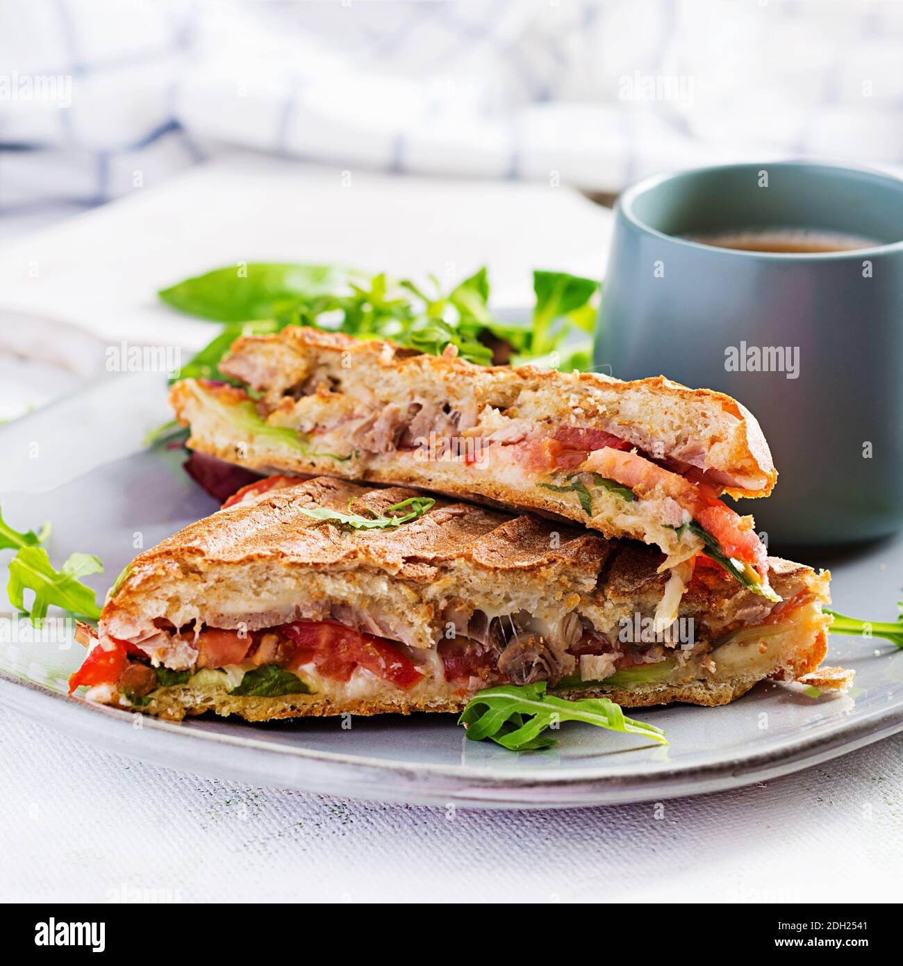 Gegrillte Club Sandwich Panini mit Rindfleisch, Tomaten, Käse, Salat und einer Tasse Kaffee. Leckeres Frühstück oder Snack. Stockfoto