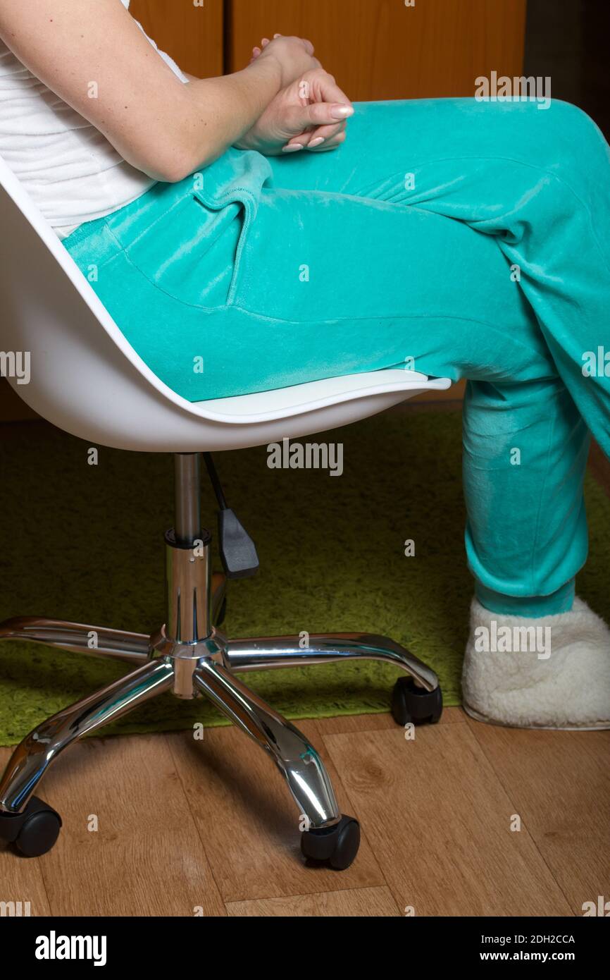 Eine Frau sitzt in einem Computerstuhl auf Rädern. In Heimkleidung. Nahaufnahme. Stockfoto