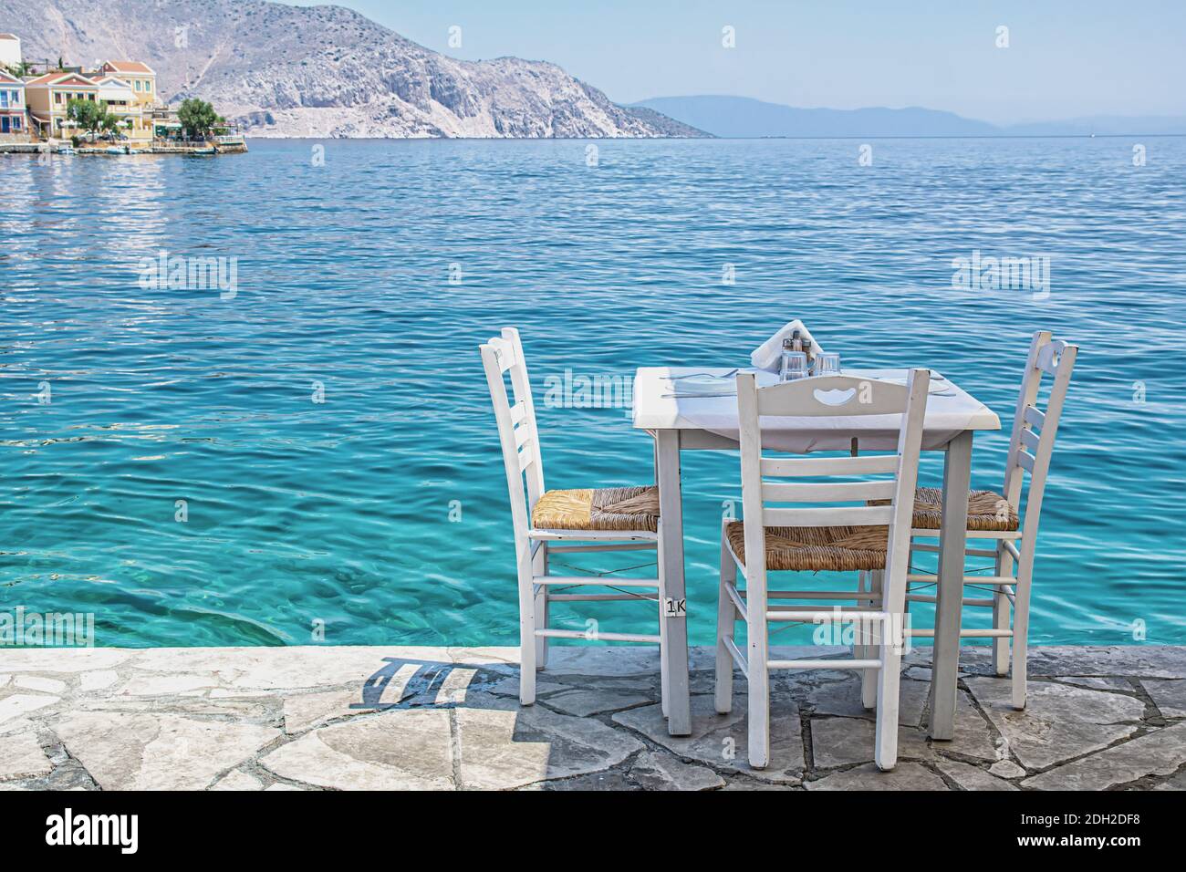 Stühle mit Tischen in typisch griechischer Taverne am Meer In Symi Stadt Stockfoto