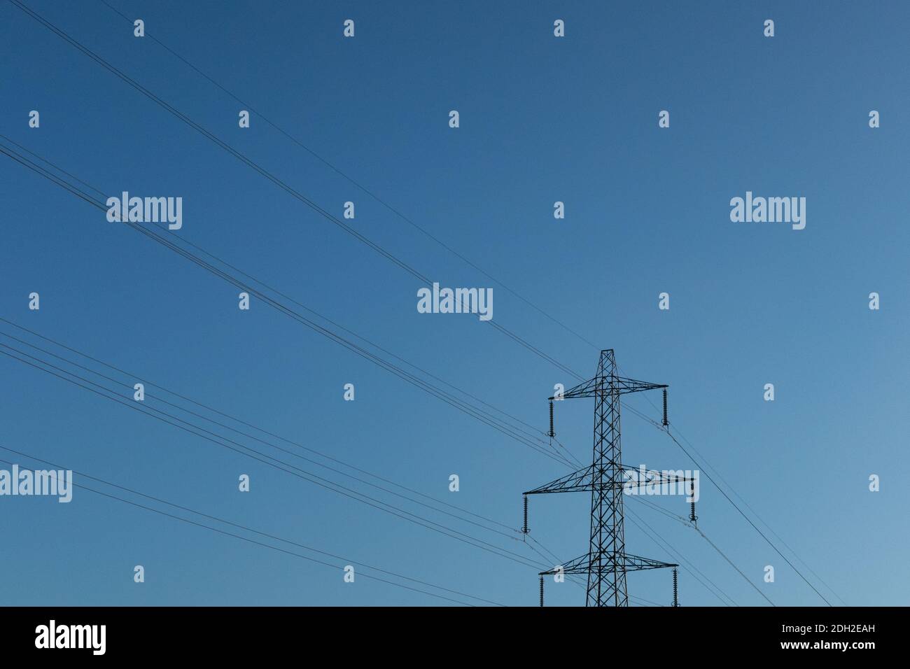 Ein Mast mit Stromkabeln, eingerahmt von einem blauen Himmel, Saddleworth, Oldham, UK Stockfoto