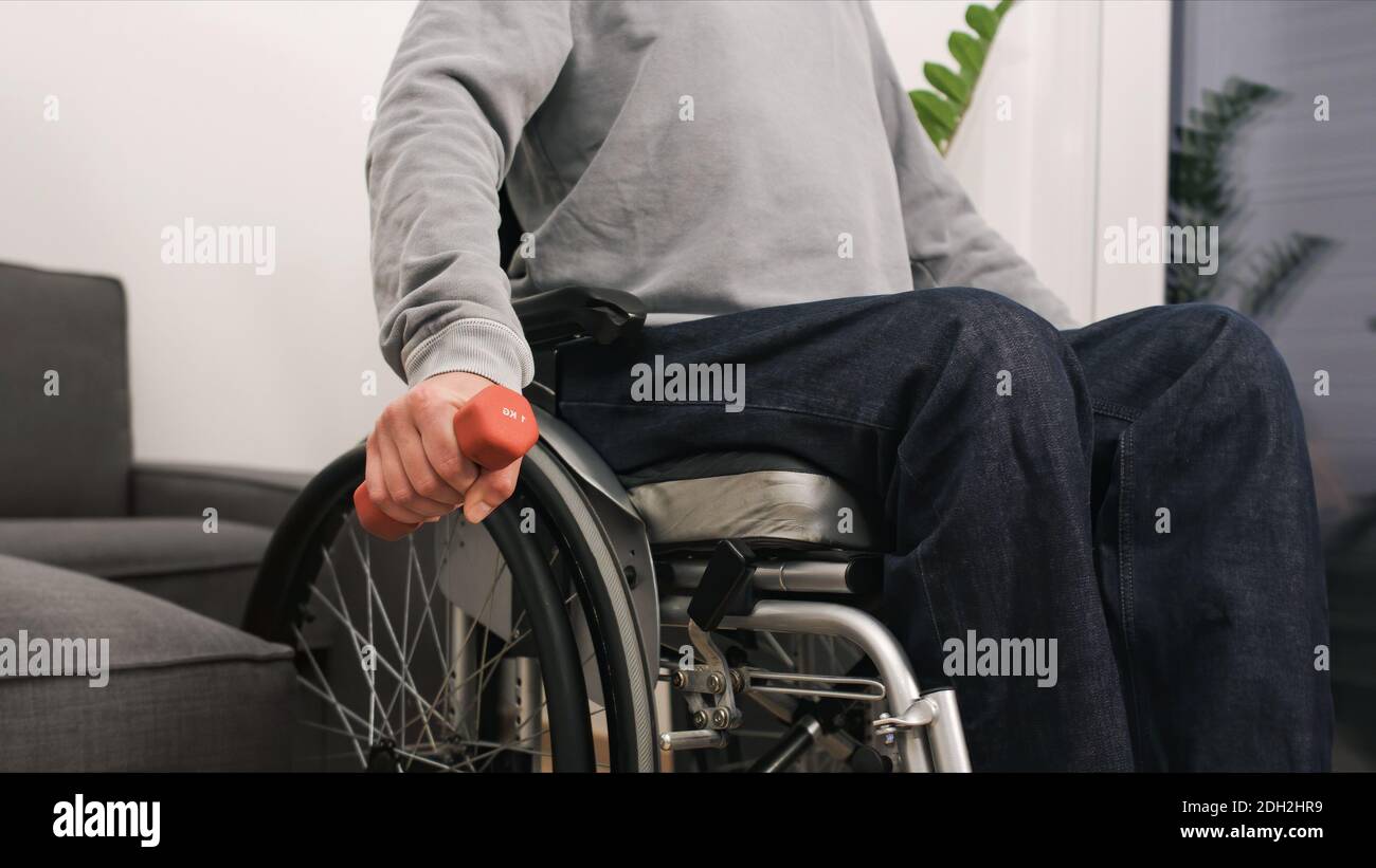 Mann im Rollstuhl Training und Gewichtheben in einem Wohnzimmer. Stockfoto