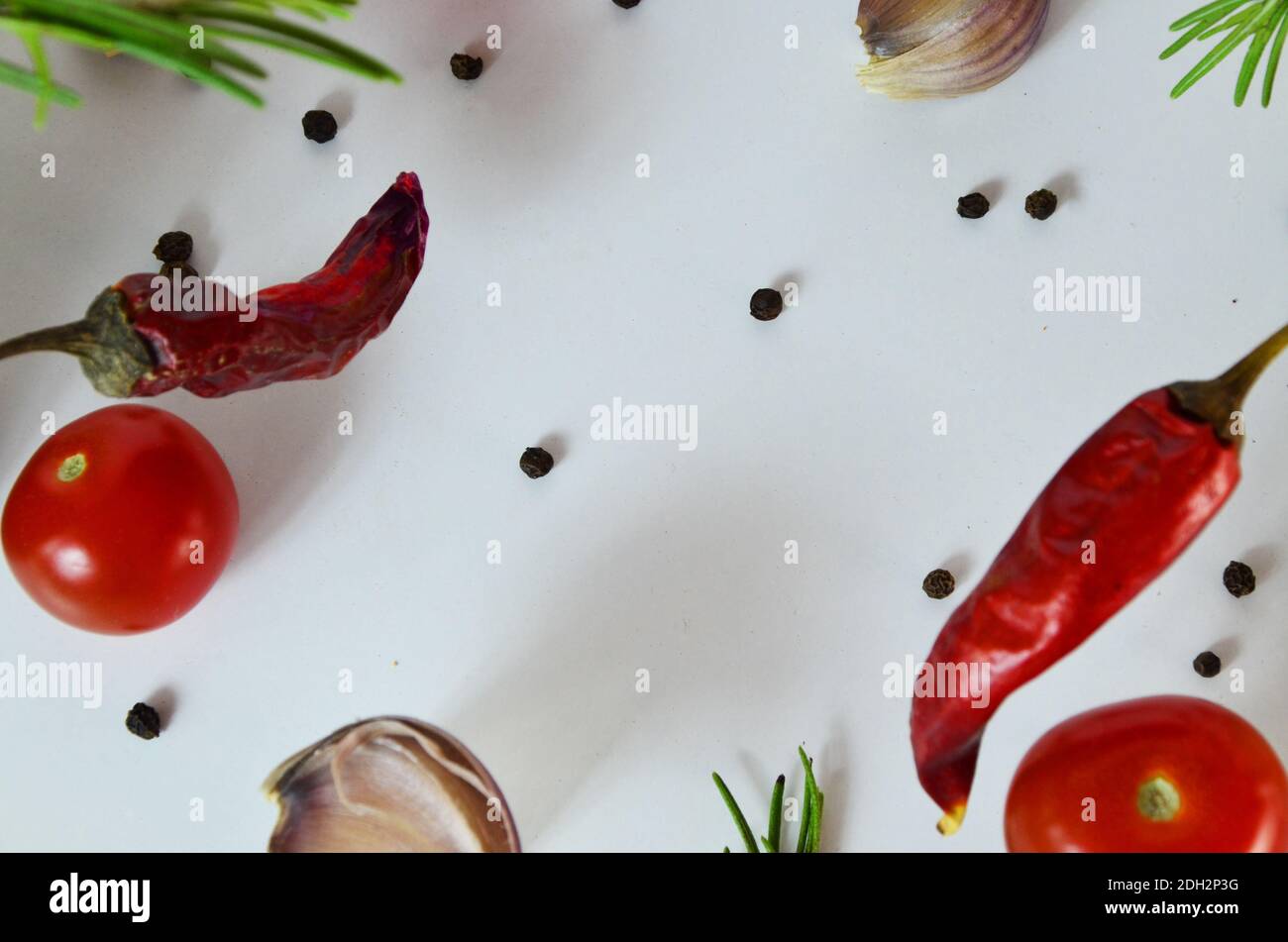 Knoblauch fällt in die Luft mit Pfeffer und Kräutern wie Rosmarin und Basilikum Blätter auf weißem Hintergrund. Würziges Food-Konzept. Abstrakter Hintergrund, kein Fokus. Stockfoto
