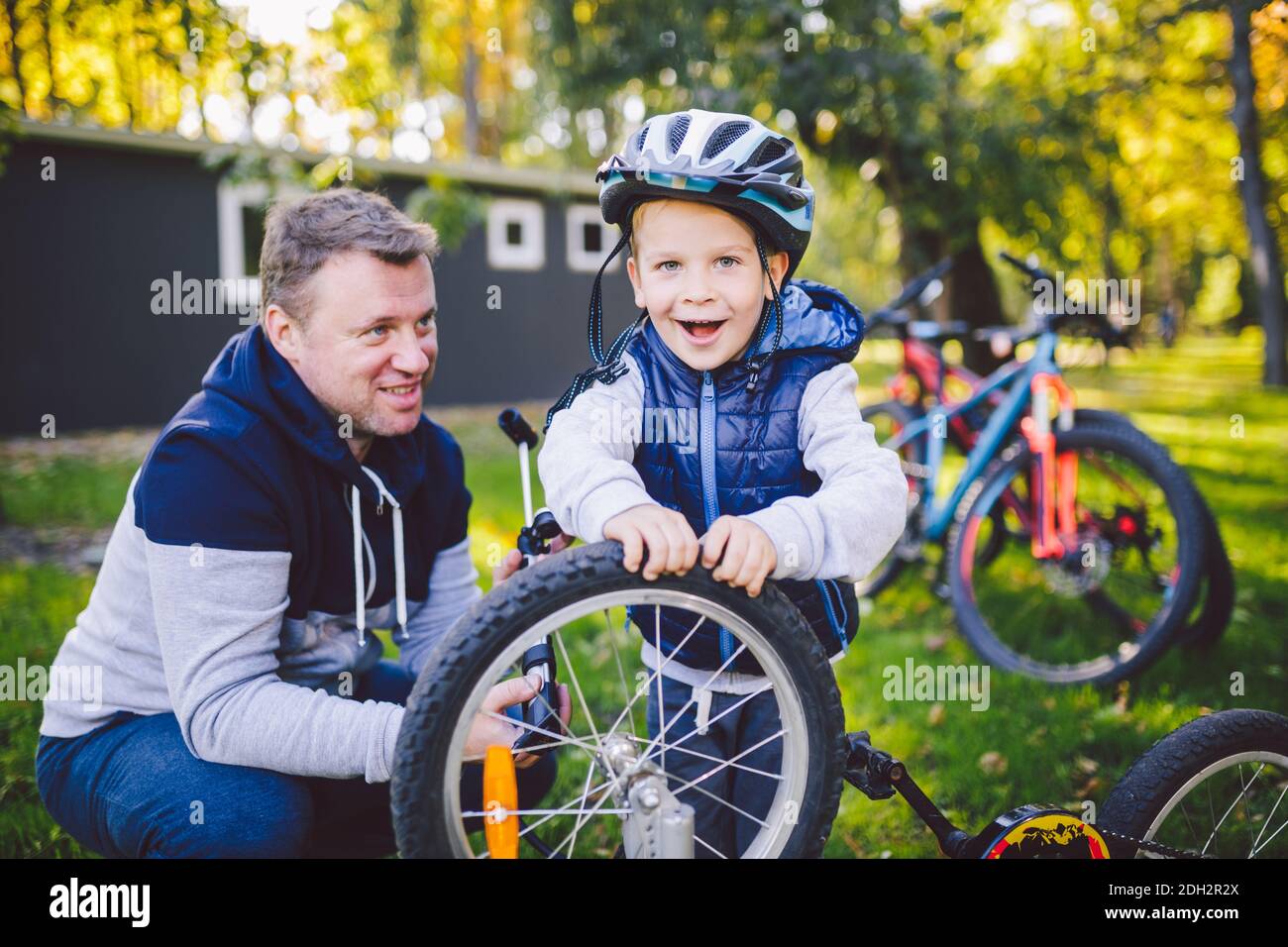 Vater's Tag kaukasischer Vater und 5 Jahre alter Sohn im Hinterhof in der Nähe des Hauses auf dem grünen Gras auf dem Rasen, der ein Fahrrad repariert, Stockfoto