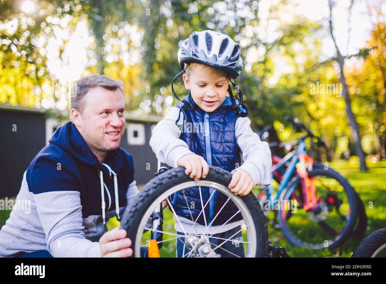 Vater's Tag kaukasischer Vater und 5 Jahre alter Sohn im Hinterhof in der Nähe des Hauses auf dem grünen Gras auf dem Rasen, der ein Fahrrad repariert, Stockfoto