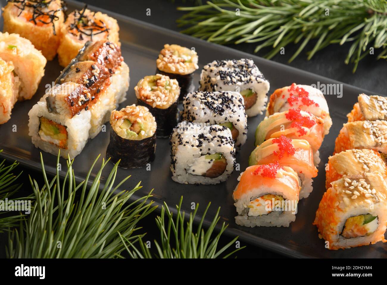 Weihnachtliches Sushi-Set mit Weihnachtsdekoration. Nahaufnahme. Weihnachtsfeier oder Neujahrsparty. Stockfoto