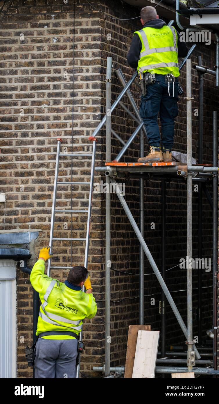 Zwei Männer, die eine Gerüstplattform zwischen den Häusern errichten. Stockfoto