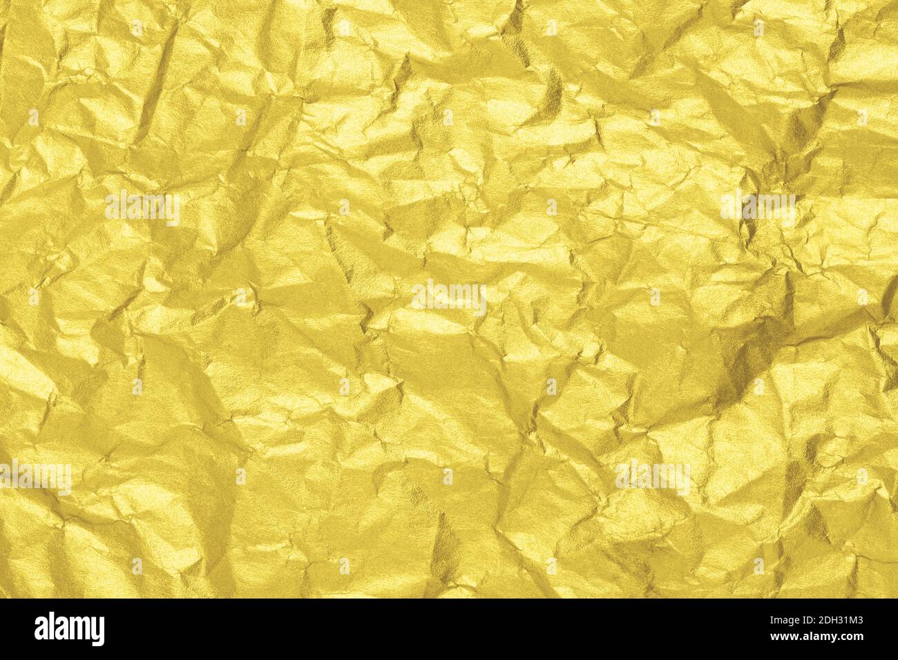Leuchtende goldene Papiertextur. Zerknittert Folie Hintergrund. Farbe des Jahres 2021. Stockfoto