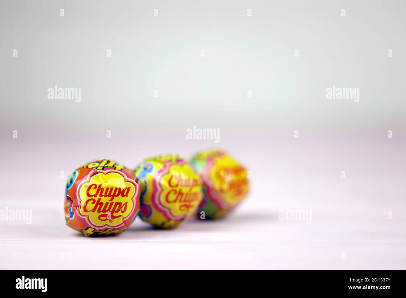 CHARKOW, UKRAINE - 24. NOVEMBER 2020: Chupa Chups Produkte auf pastellrosa Holztisch. Chupa Chups ist eine spanische Marke von Lollipop und anderen confectio Stockfoto