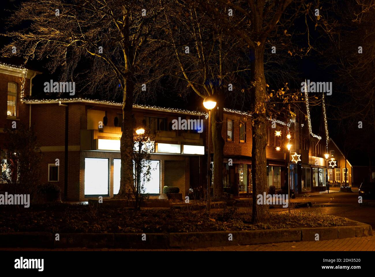 Eine kleine deutsche Stadt in der Weihnachtszeit. Es wird dunkel. Geschäfte, Häuser, Bäume und Weihnachtsbeleuchtung Stockfoto