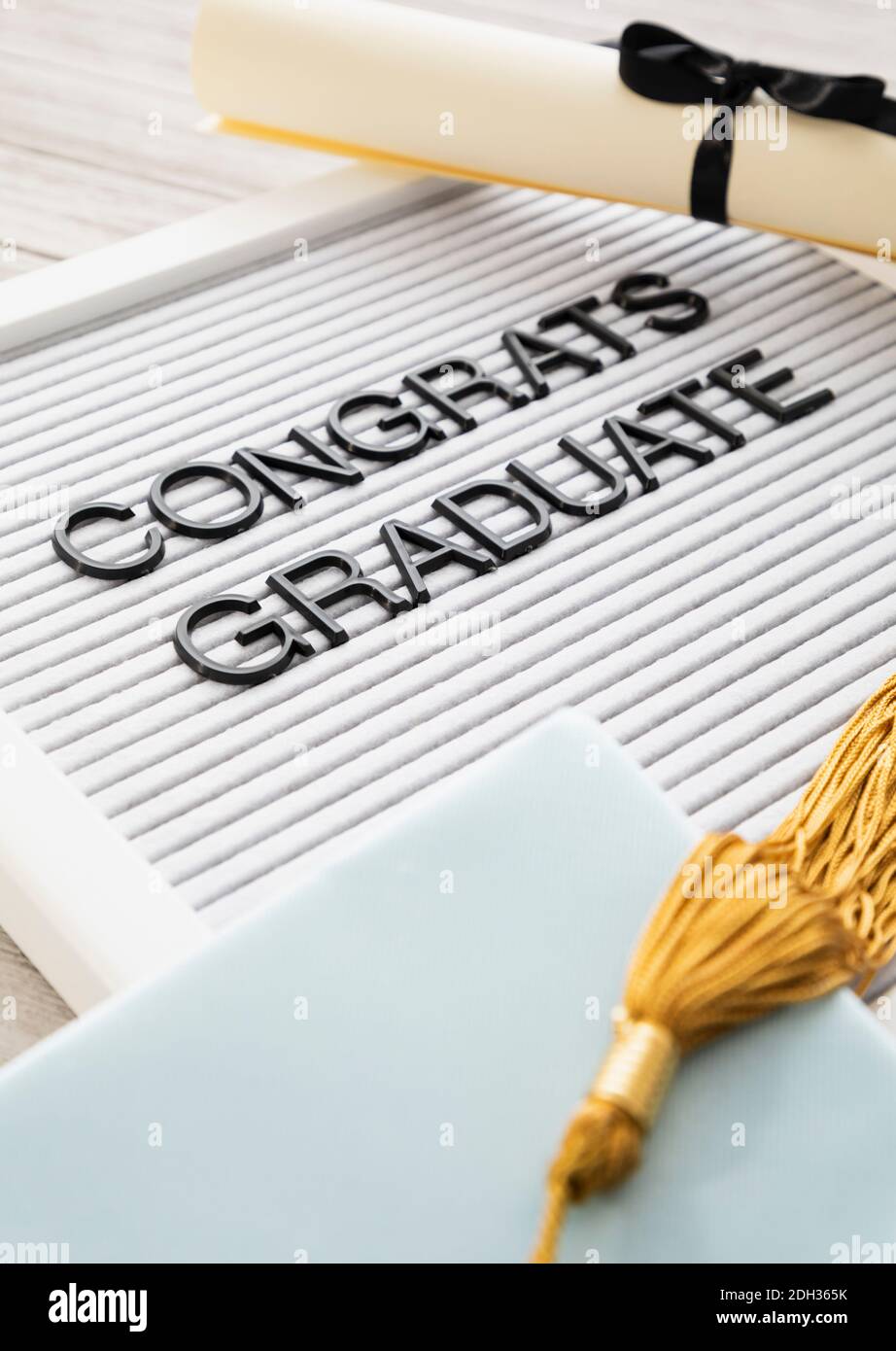 Feier der akademischen Leistung mit einer Abschlusskappe, einem Diplom und einer Gratulationsbotschaft Stockfoto